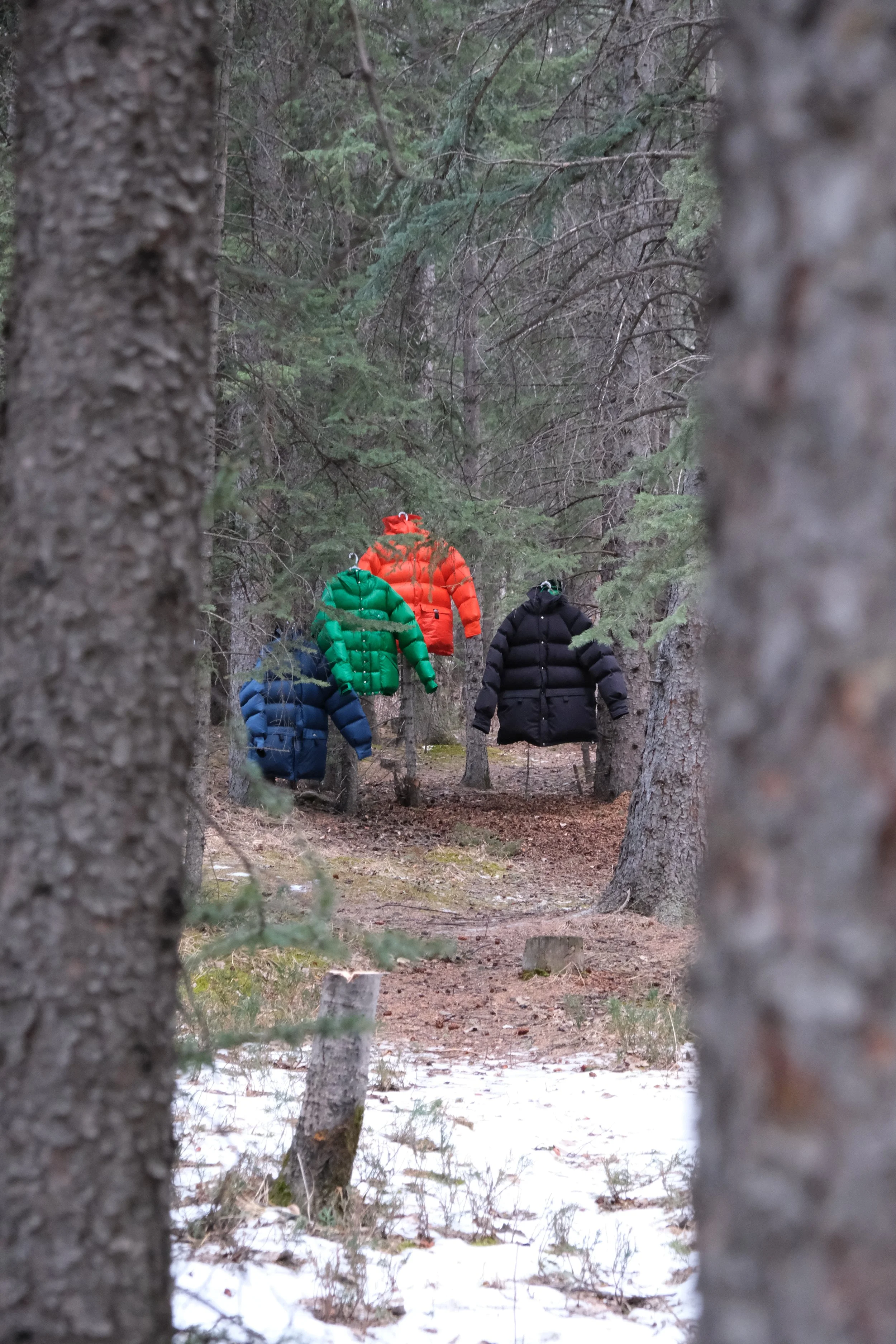 Four Kluane down jackets photographed hanging among trees