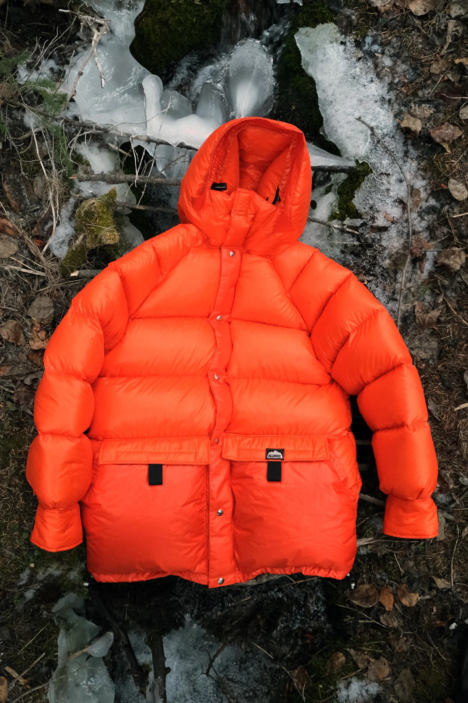 Orange Outer Parka beside frozen creek
