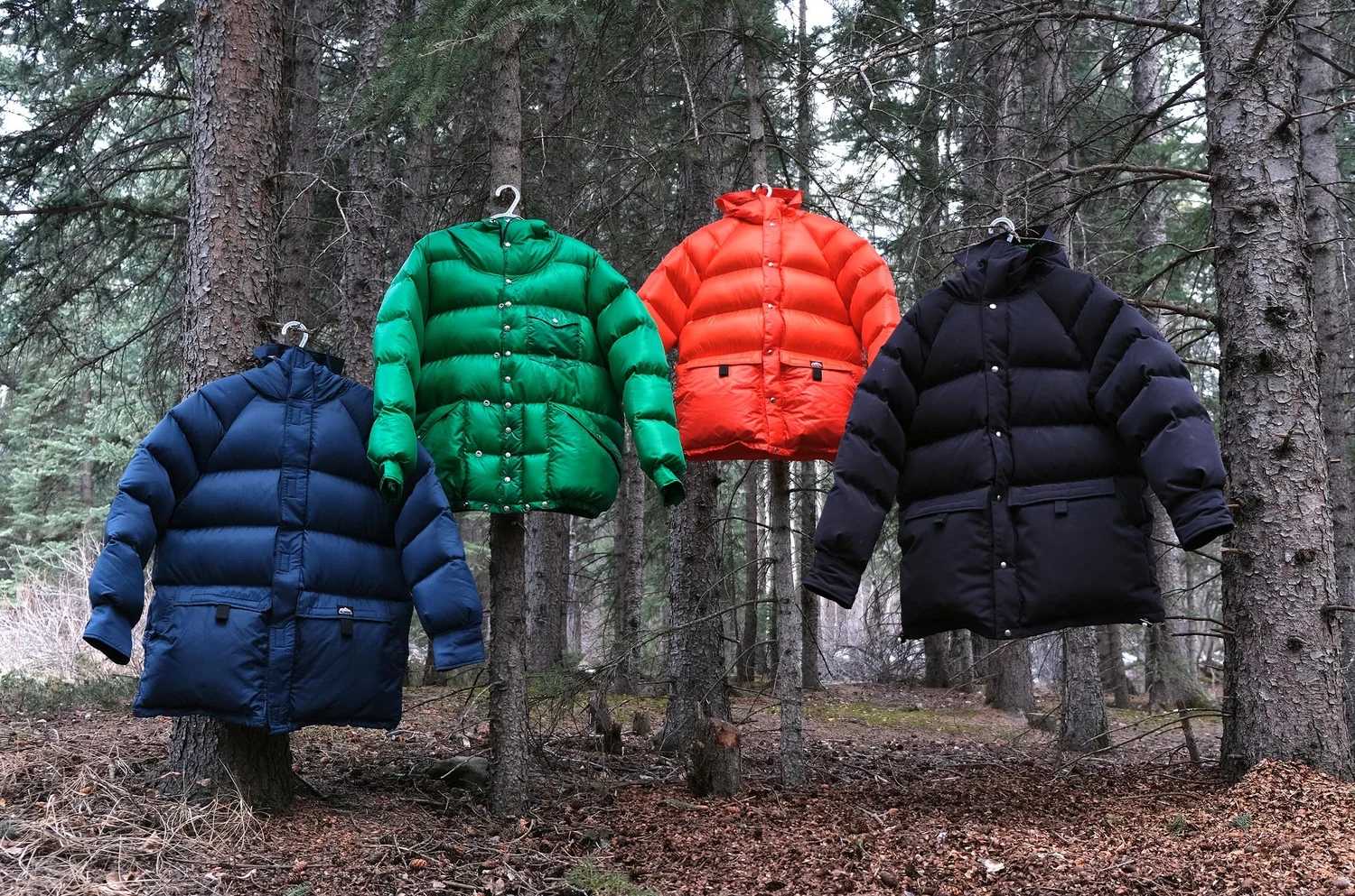 Four Kluane Outer Parkas hanging in forest