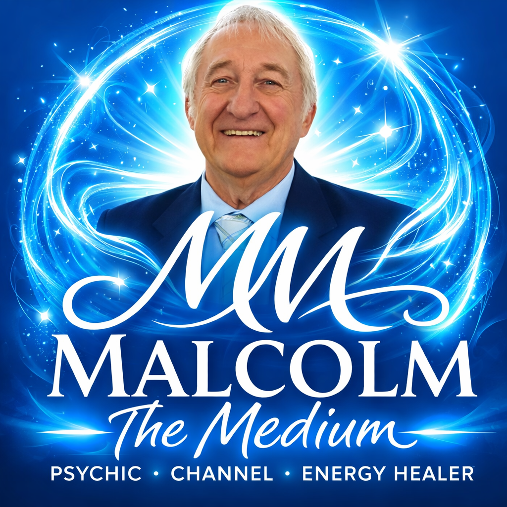 Elderly man smiling in front of lush green foliage, wearing a checkered shirt.