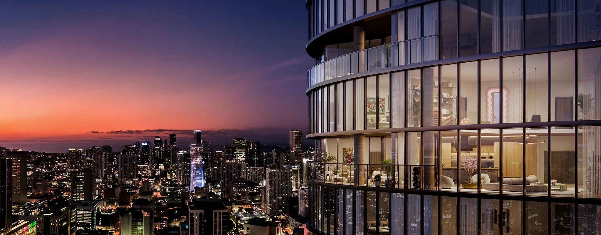 A tall modern high-rise building with glass walls overlooking a city skyline at sunset.
