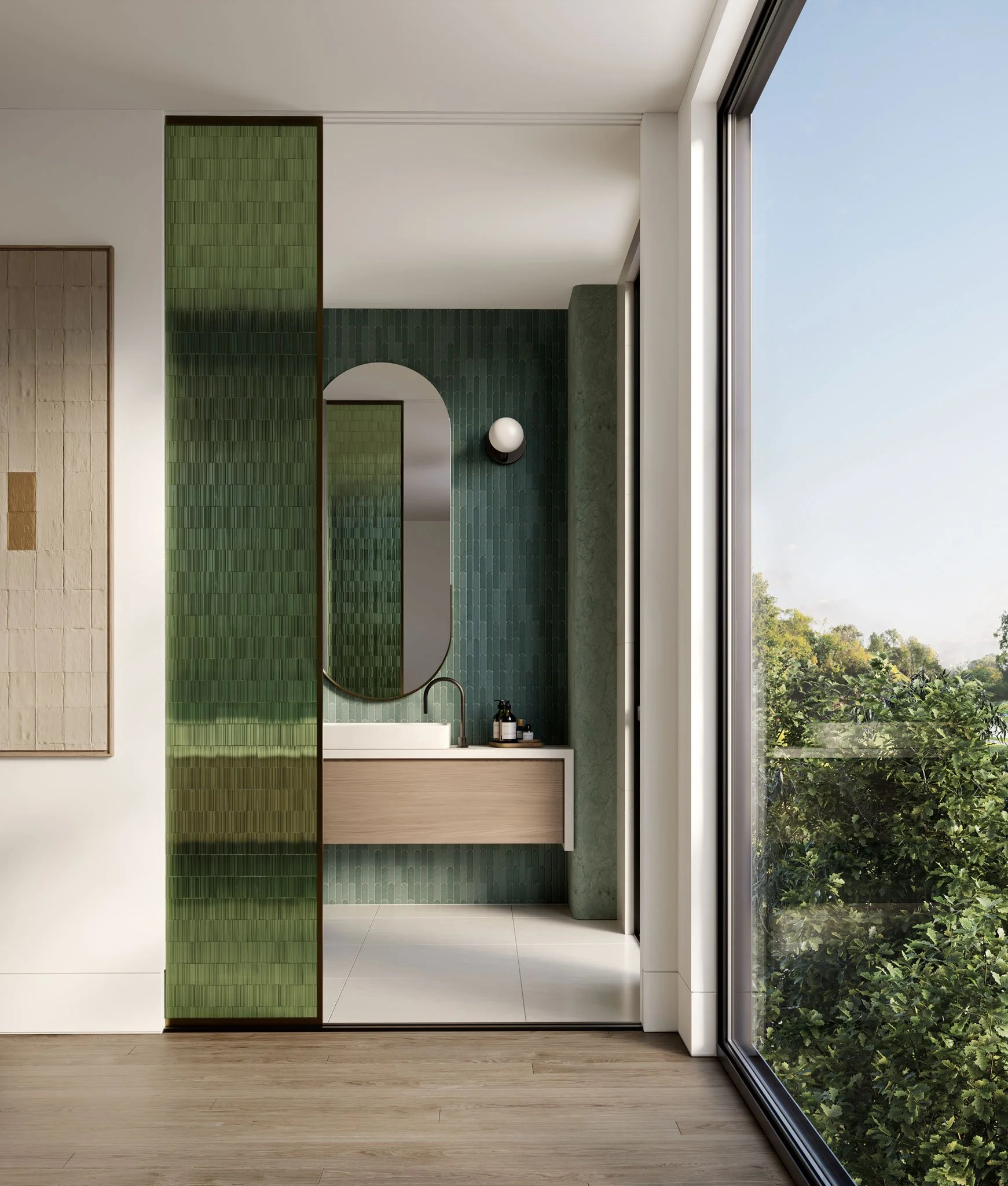 Modern bathroom with green textured wall tiles, a mirror, a white sink with black bottles on a wooden vanity, and a large window showing greenery outside.