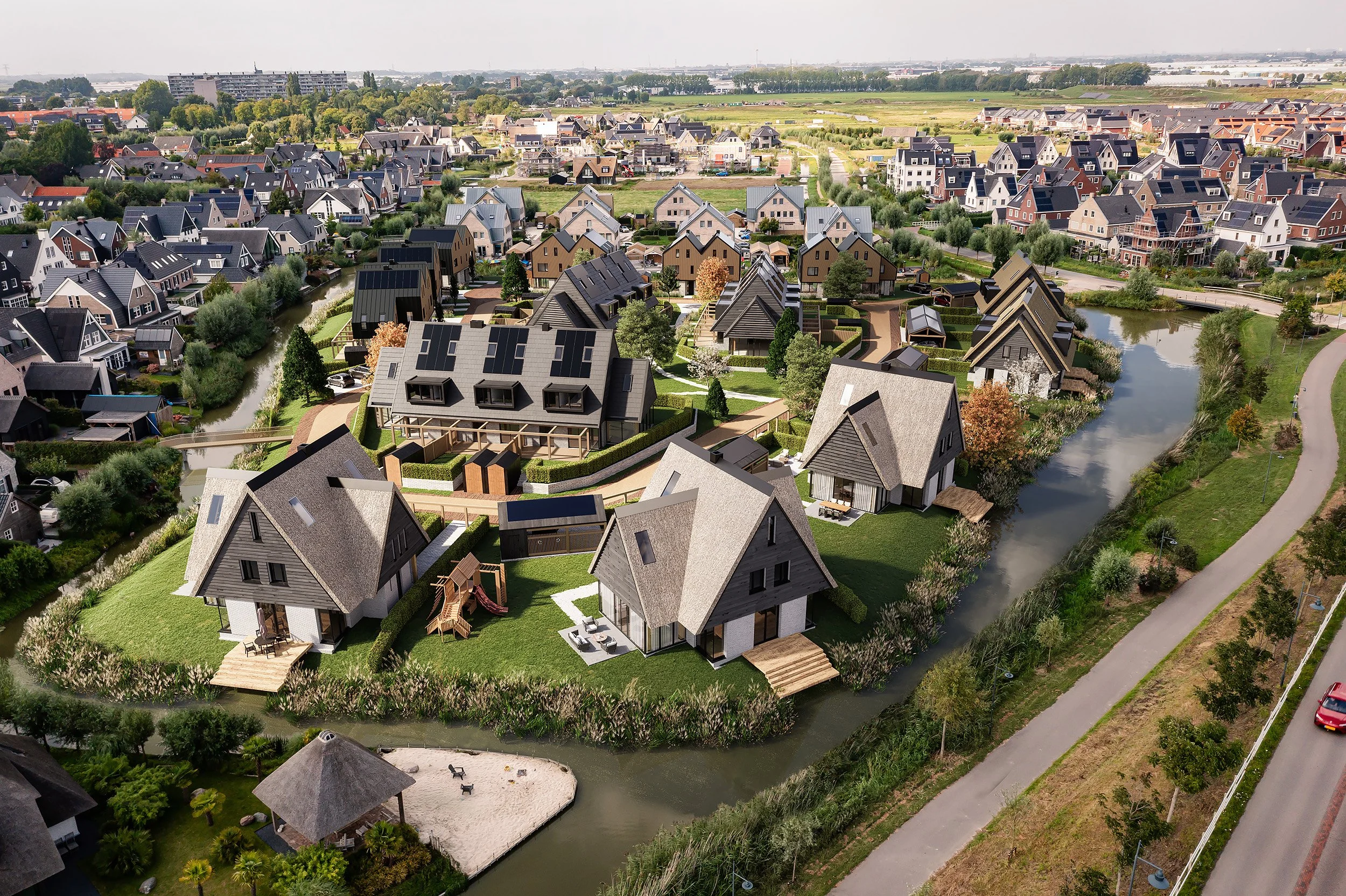 Aerial view of a modern residential neighborhood with houses surrounded by waterways, greenery, and trees.