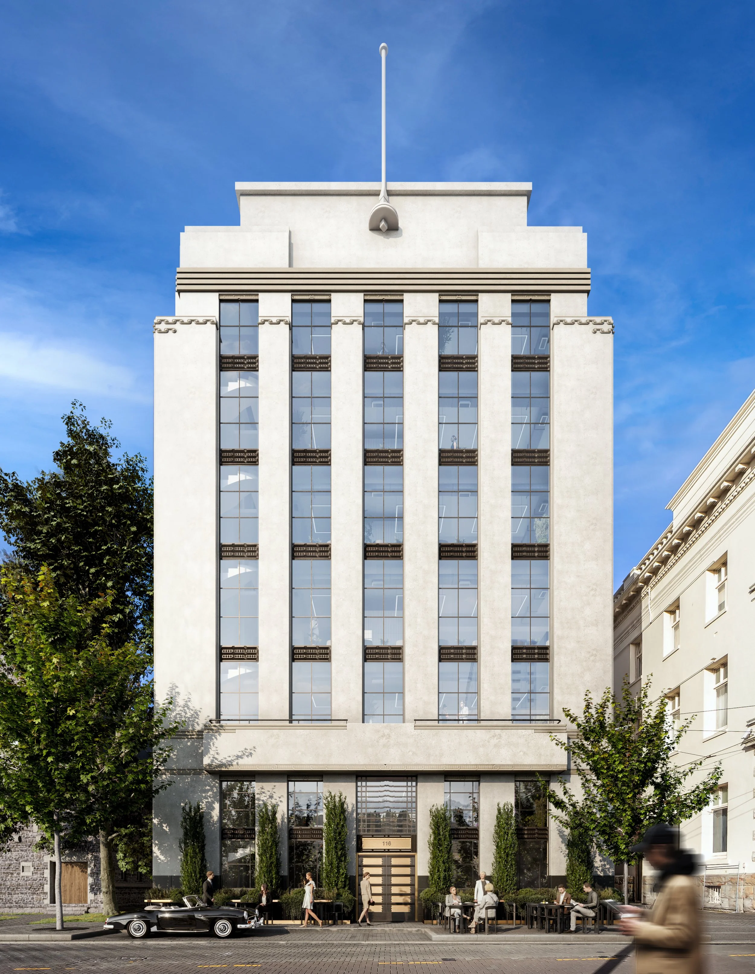 Tall modern office building with reflective glass windows, surrounded by trees, with people walking and sitting outside, and a vintage car parked on the street in front.