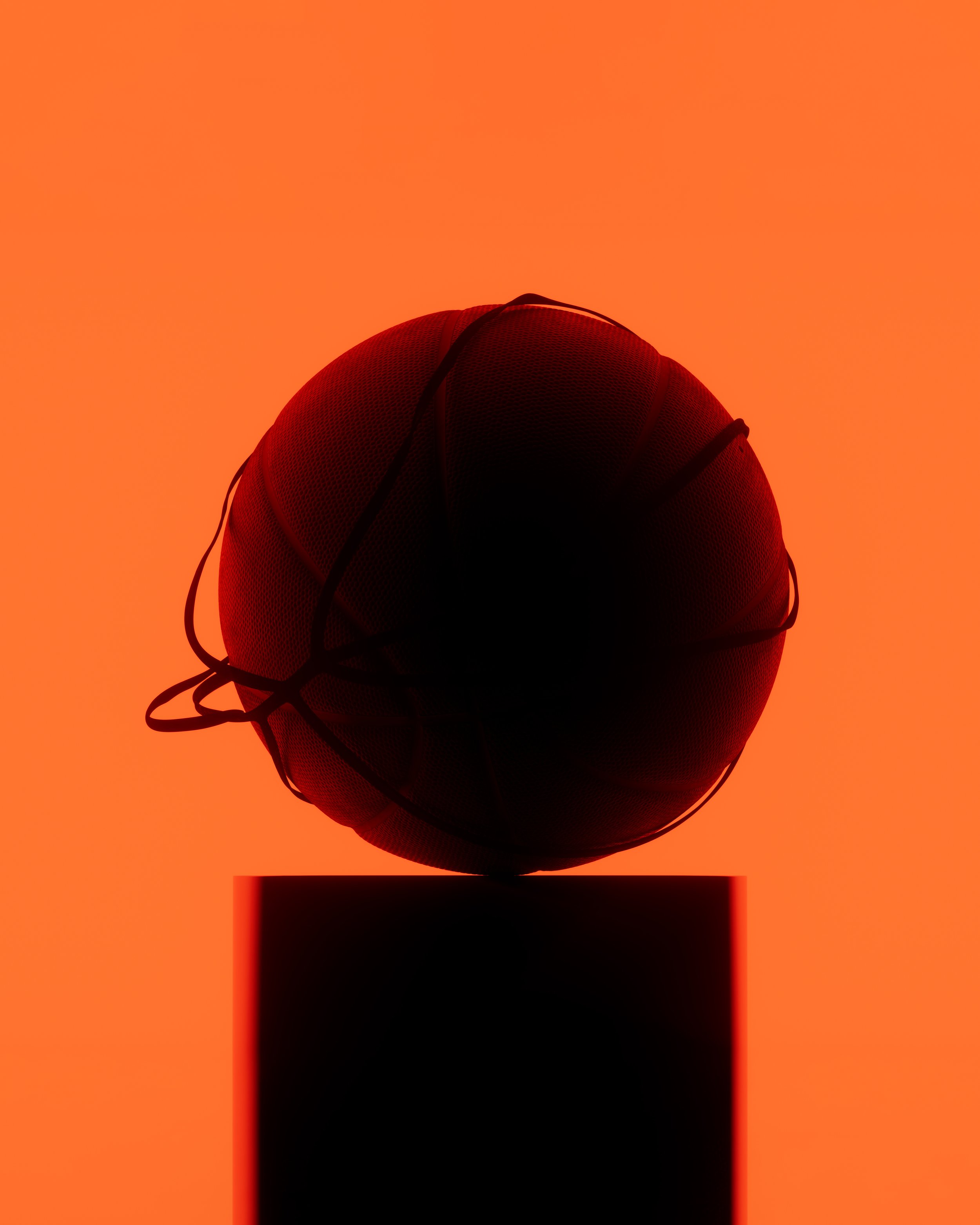 Silhouette of a basketball on a pedestal against an orange background.