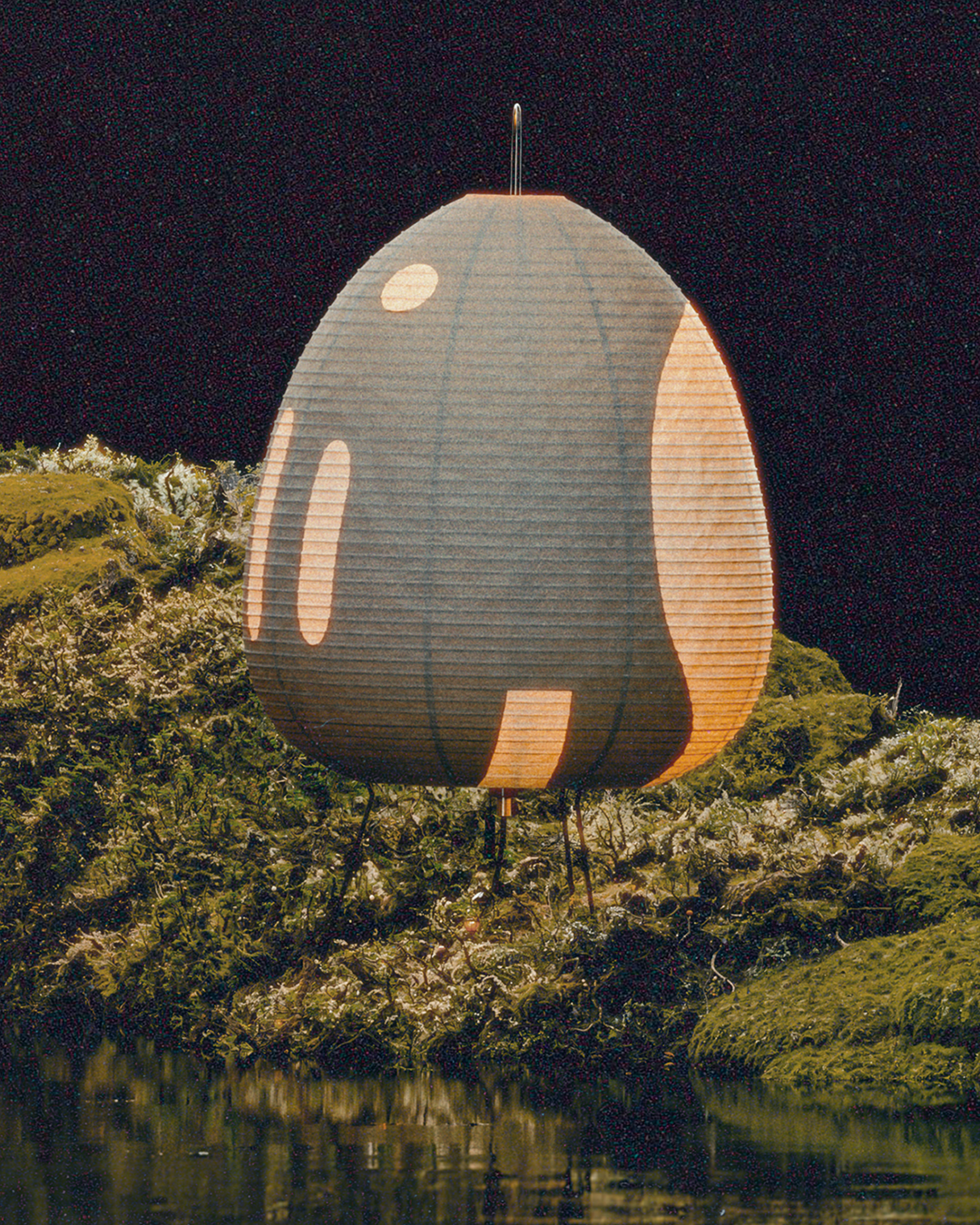 Large paper lantern floating above lush green terrain at night. ISAMU NOGUCHI AKARI