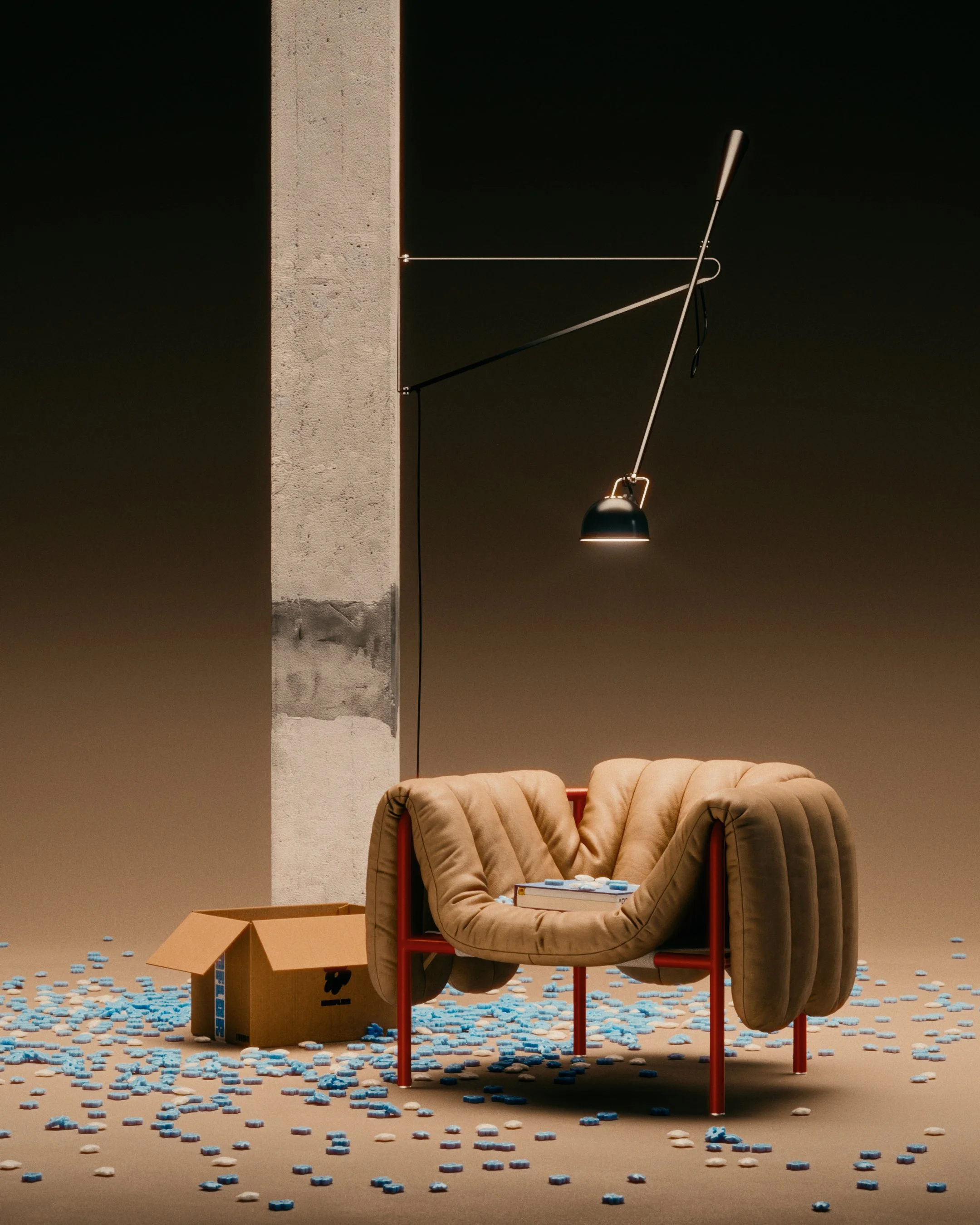 A modern beige armchair with red metal legs placed in a minimalist space, with a book resting on it, next to a wooden box and a tall concrete pillar. PUFFY.LOUNGE. HEM. FAYE TOOGOOD. DESIGN CHAIR