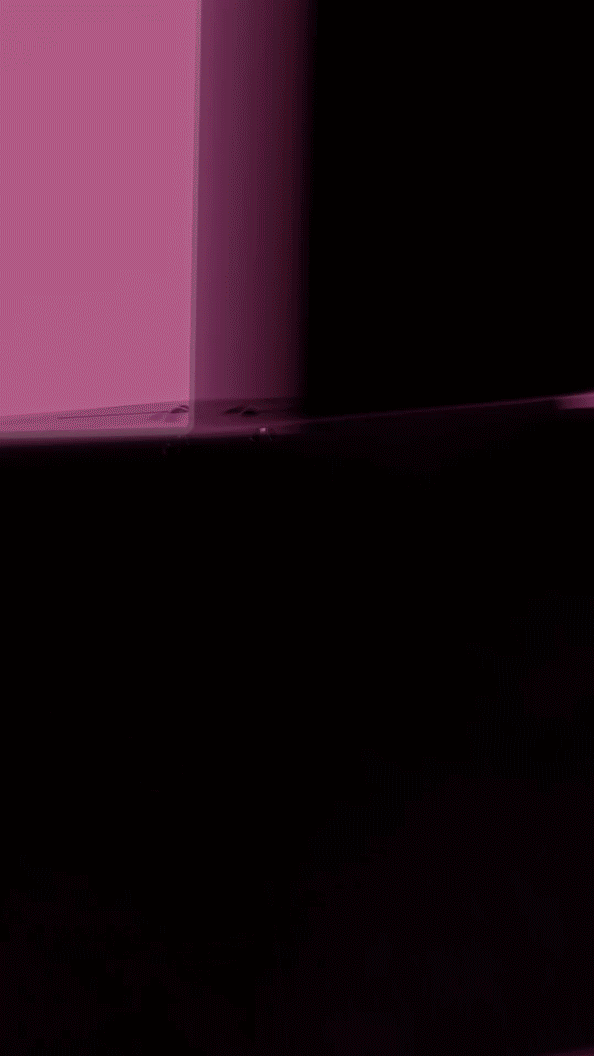 Close-up of a pink and black electronic device with a glossy surface, reflecting light.