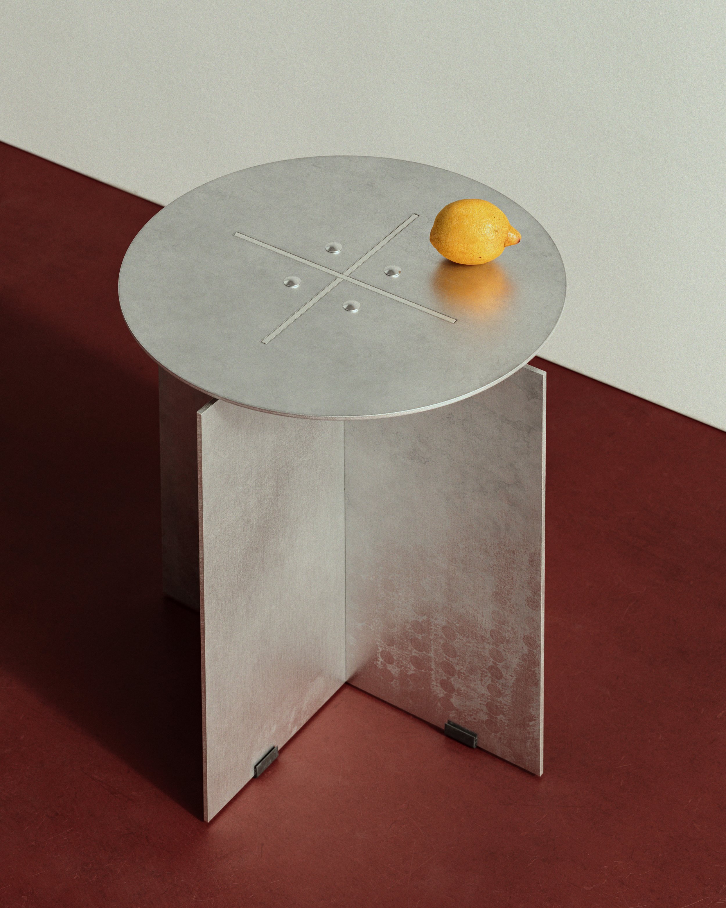 A round metallic table with a lemon on top, positioned against a beige wall on a red floor. LOES BETA GMBH
