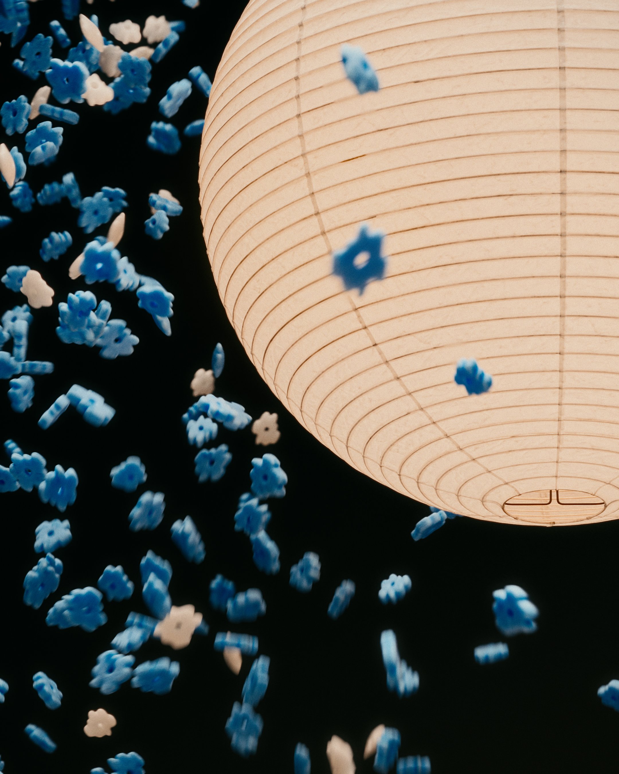 A illuminated paper lantern with a scattering of blue and white confetti against a dark background.