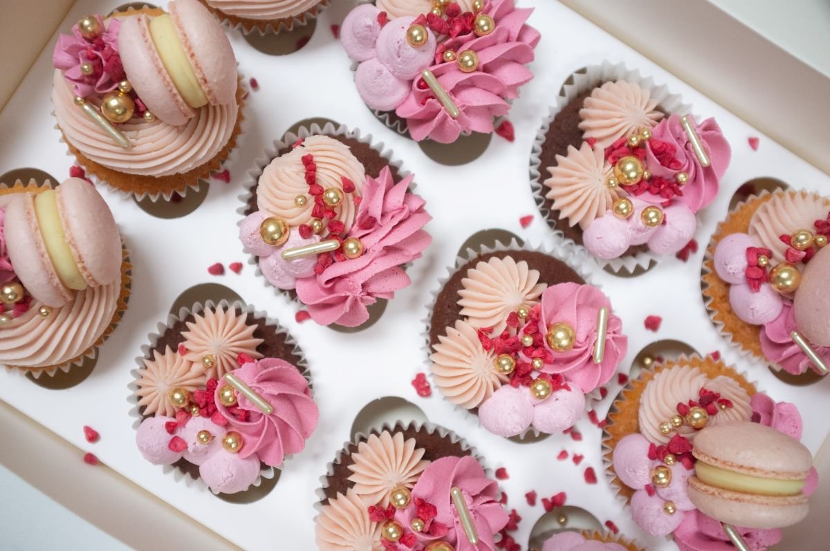 Box of pink cupcakes with macarons and sprinkles