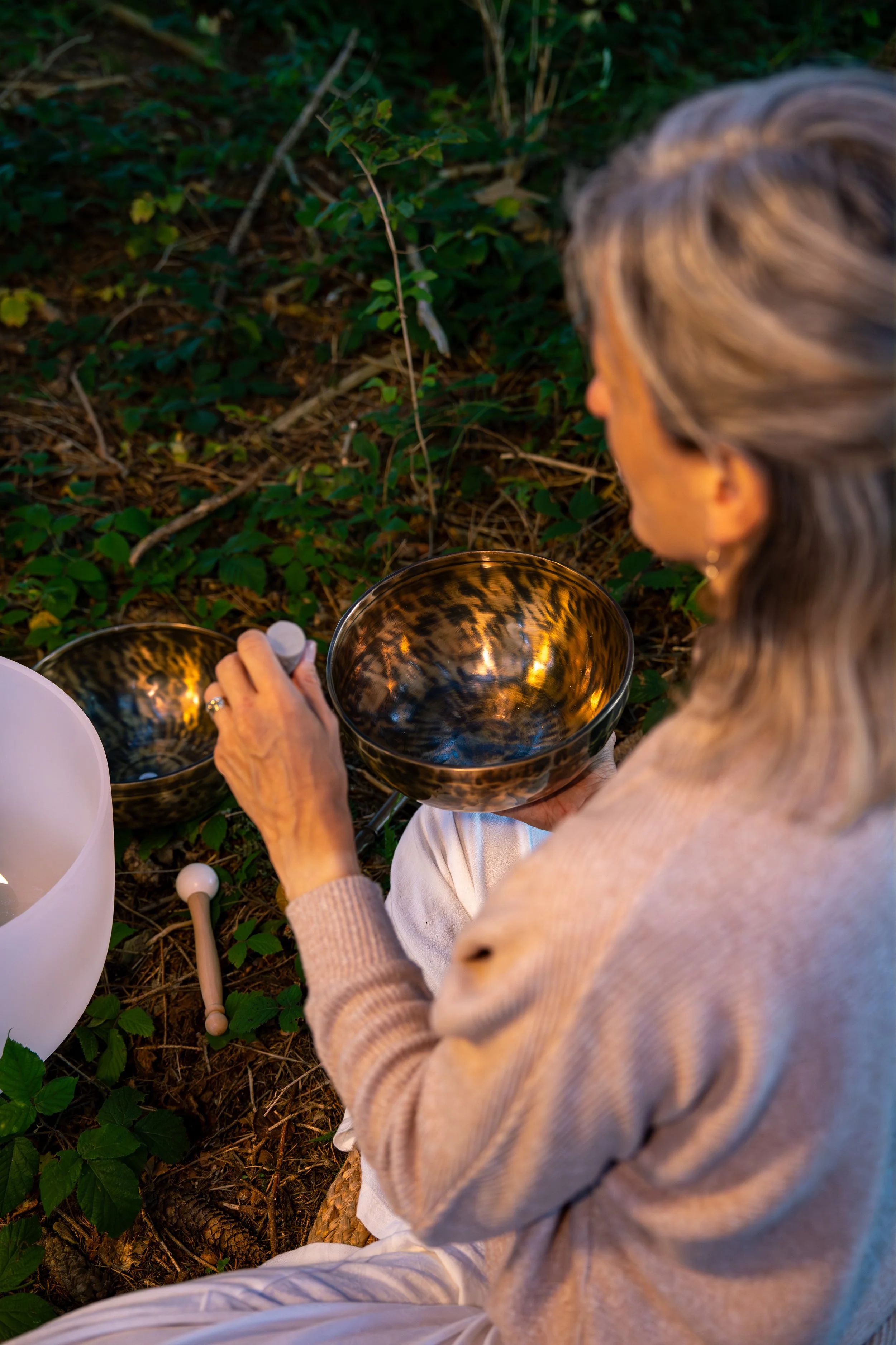 Soundhealing Yoga in Wil – Frau sitzt im Schneidersitz mit Tibetschale, Kristallschale auf dem Boden im Wald