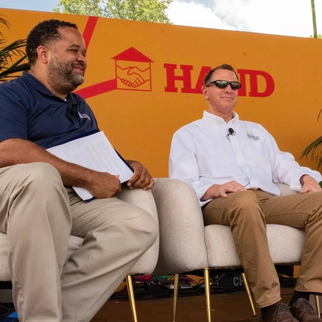 Panelists seated on stage during a Housing& event, engaging in a discussion about community development and housing.