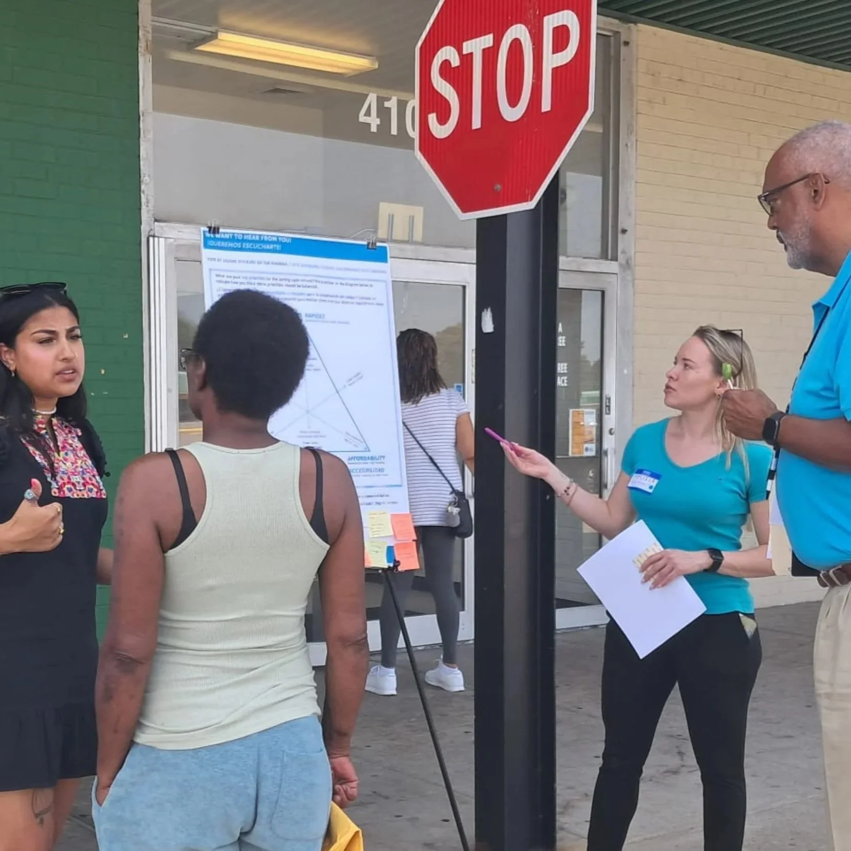 Facilitators and community members discussing rezoning proposals and viewing informational posters displayed outdoors during a public outreach event.
