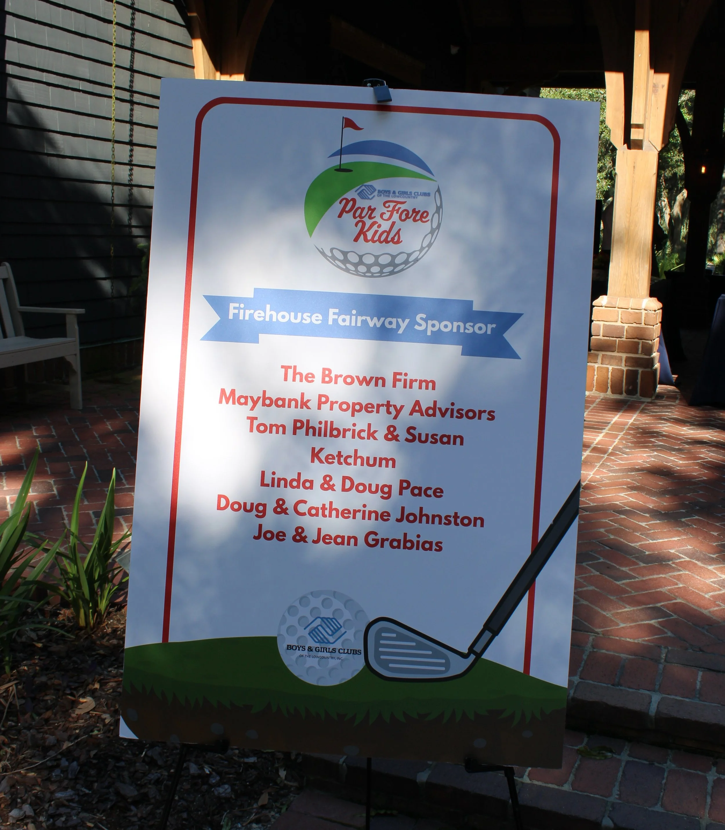 A sign with a golf ball and club illustration, indicating sponsorship for a Kids' golf event, with the Boys & Girls Clubs of the Lowcountry logo and the text 'Par For Kids'.