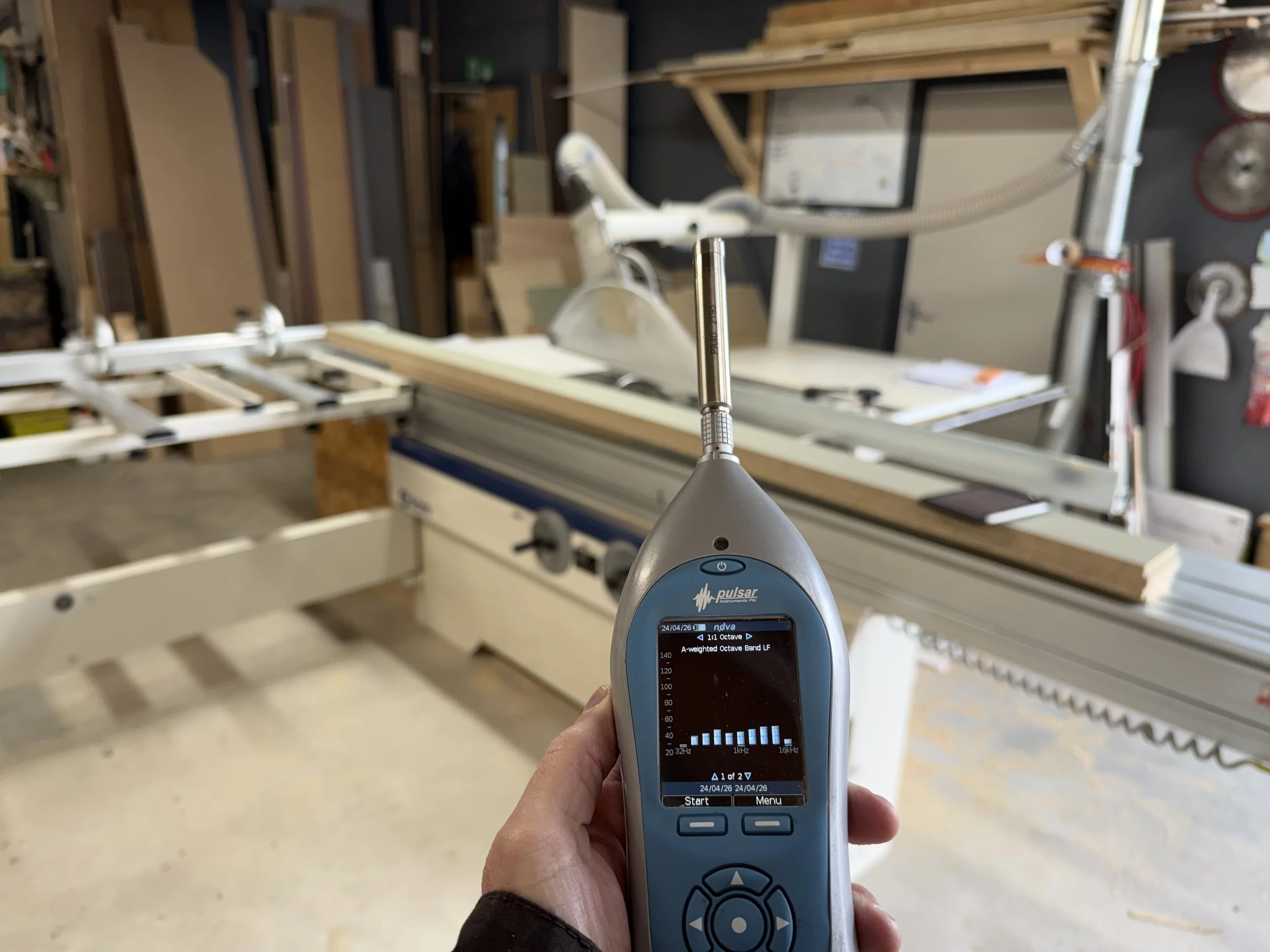 Noise meter being held in front of a table saw during a noise assessment
