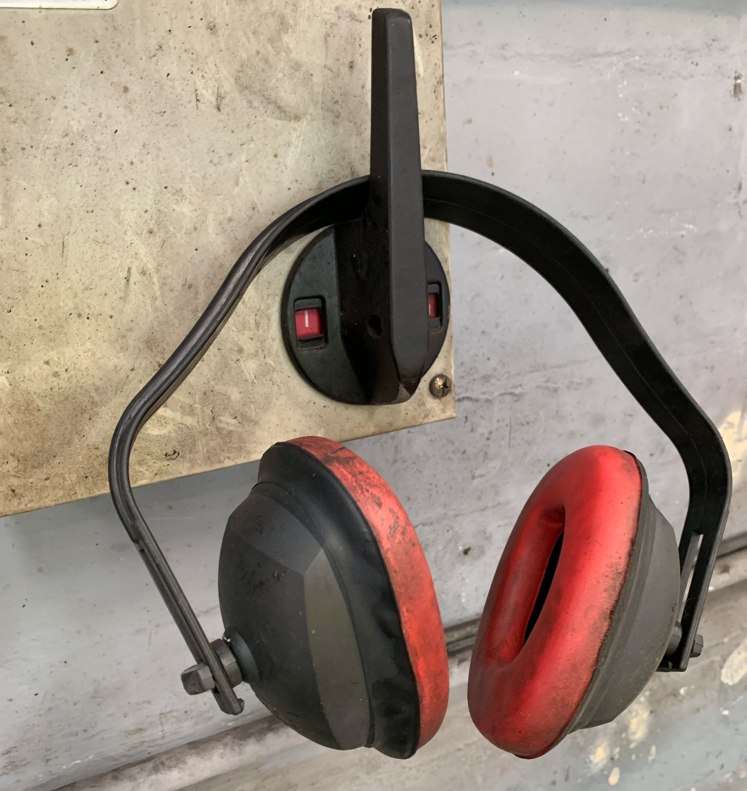 Dirty ear muffs hanging on the isolation switch of a control panel