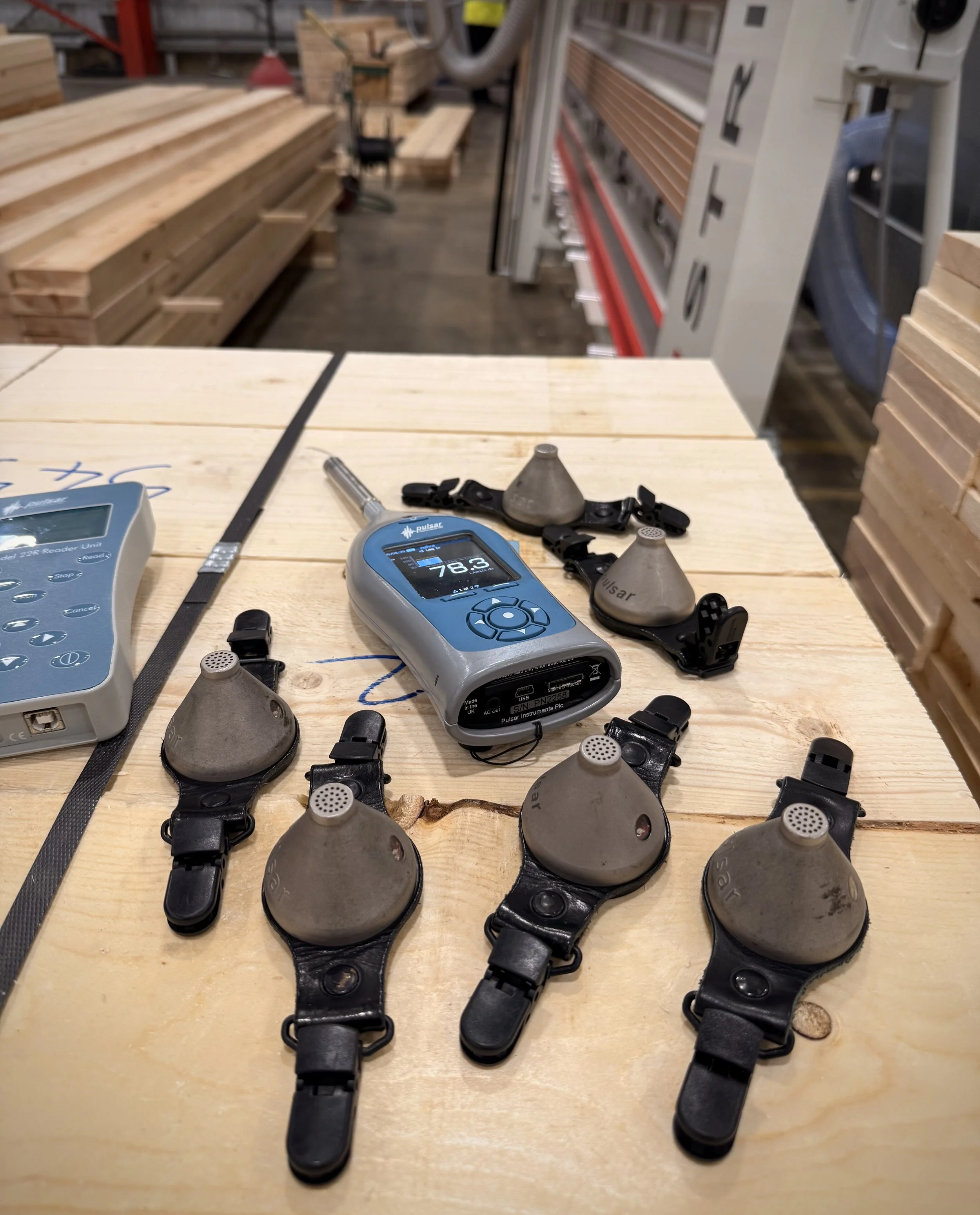 Noise meter and six dosemeters on a table for a noise assessment