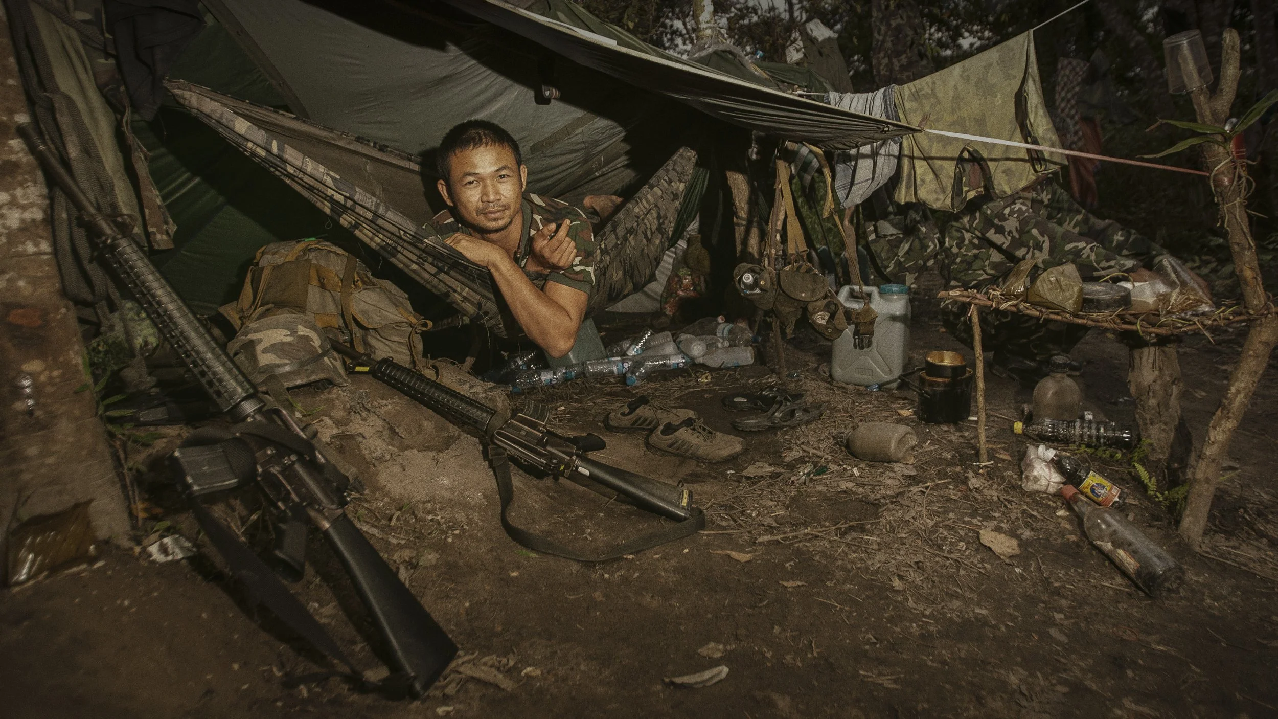An evening portrait as this RCAF soldier embraces what comfort the hammock affords him along this mountaintop trench line.