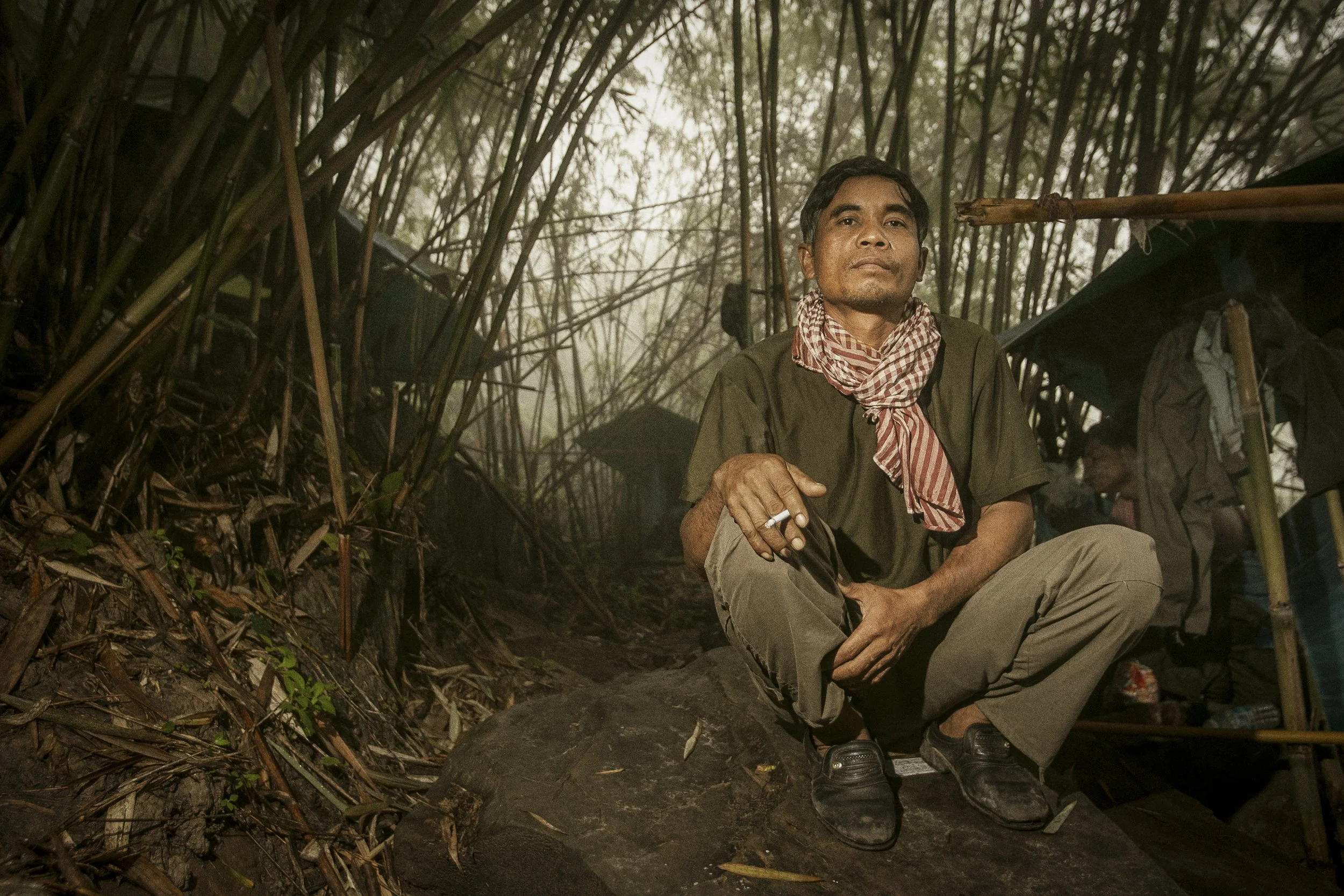 An RCAF soldier in the dense bamboo jungle outside of his camp enjoying a morning cigarette.