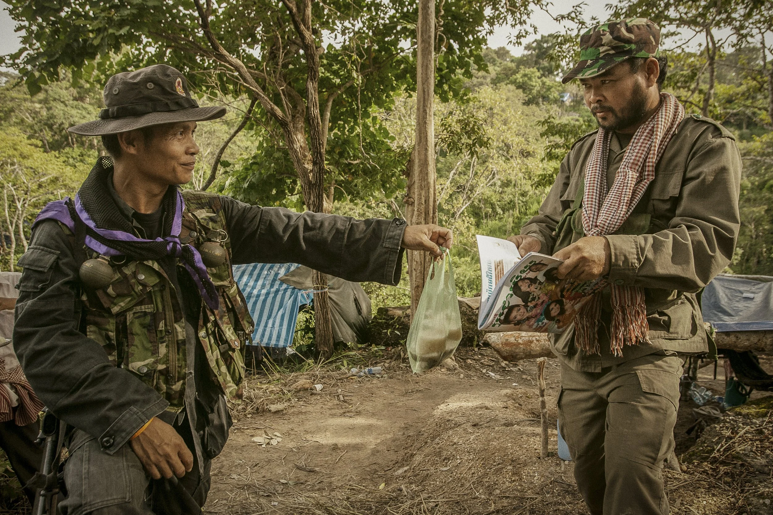 This Thai Sergeant offers his Cambodian counterpart an afternoon snack reaching across one of several trenches that snake through this contested border zone.