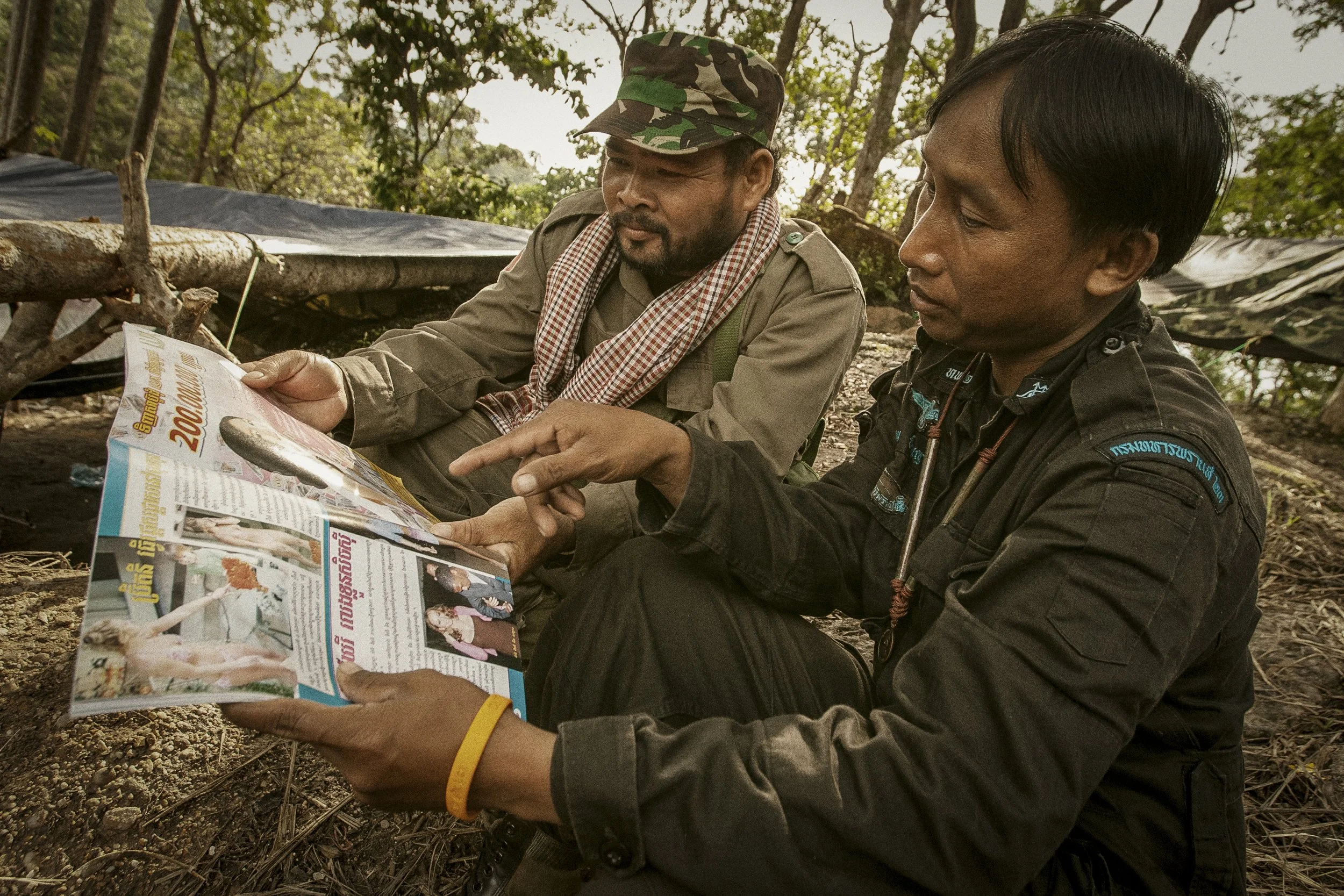 Taking time to embrace some neutrality not far from their respective trench and bunker networks, these Cambodian and Thai troops share and discuss an article in a popular entertainment magazine. 