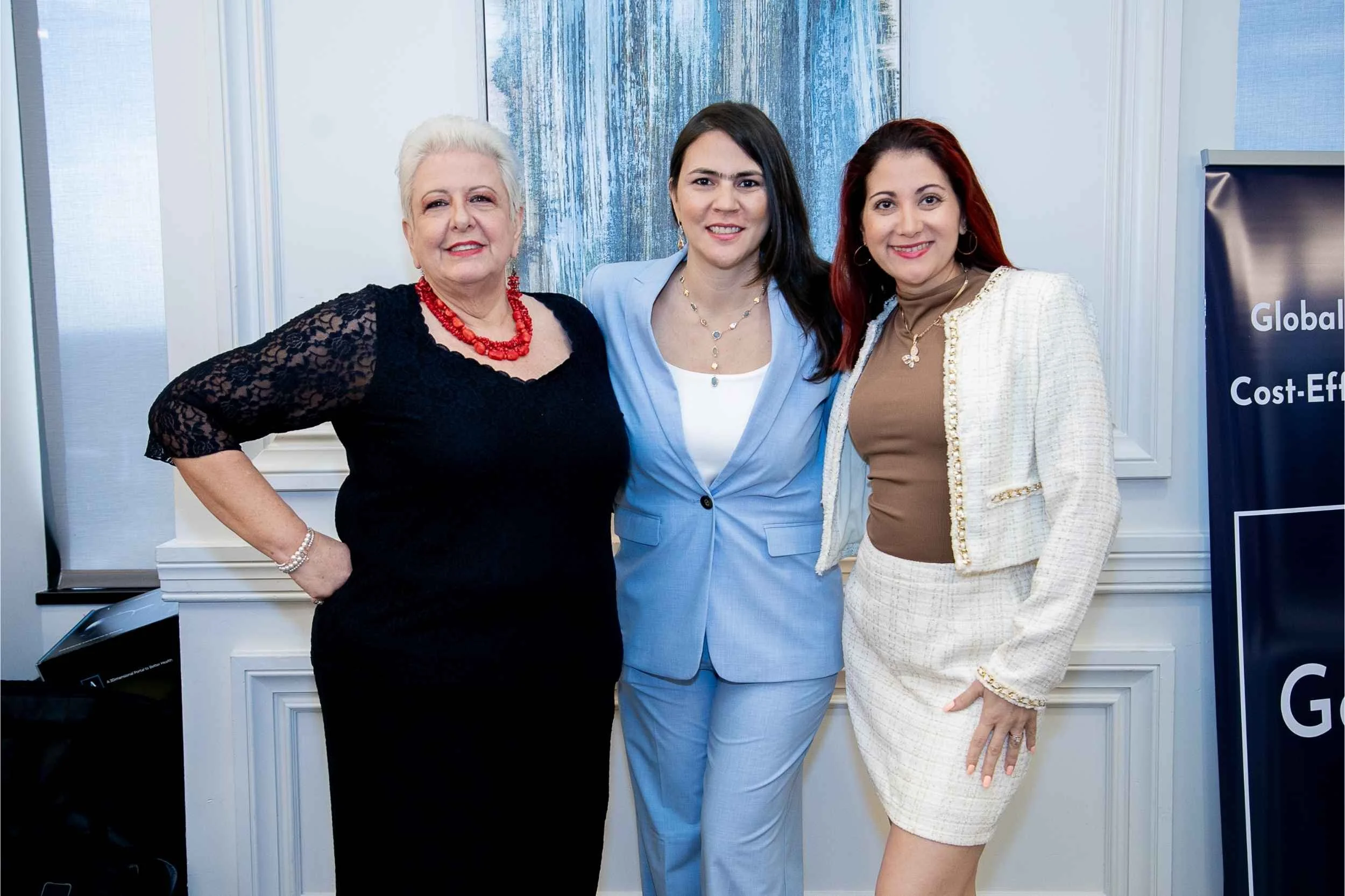Three women dressed in business attire standing together in a conference room, smiling for a photo for a conference photographed by Cannonfire Photography in Orlando.