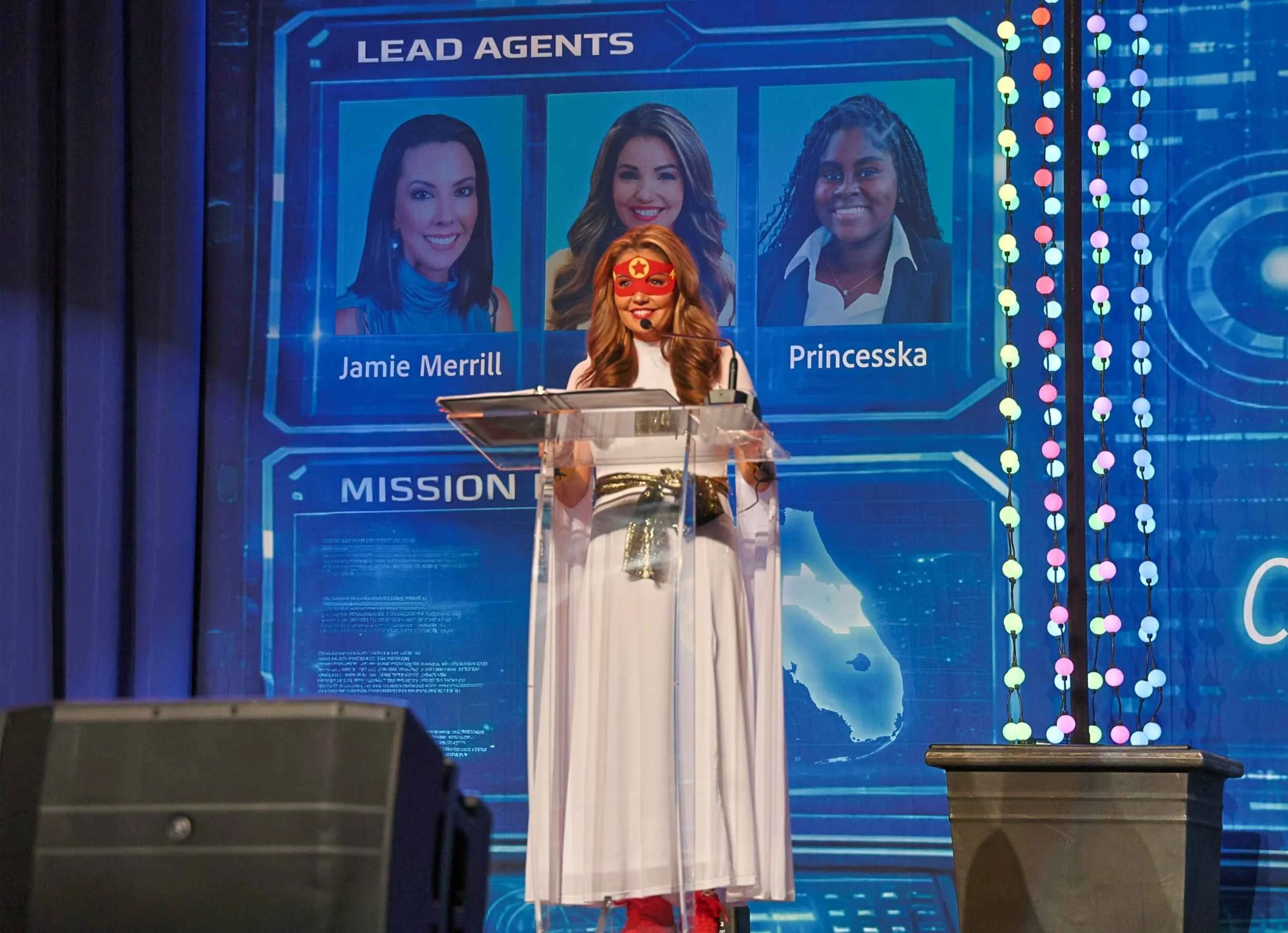 Presenter speaking on stage behind a podium with event screens behind them at the Orlando gala