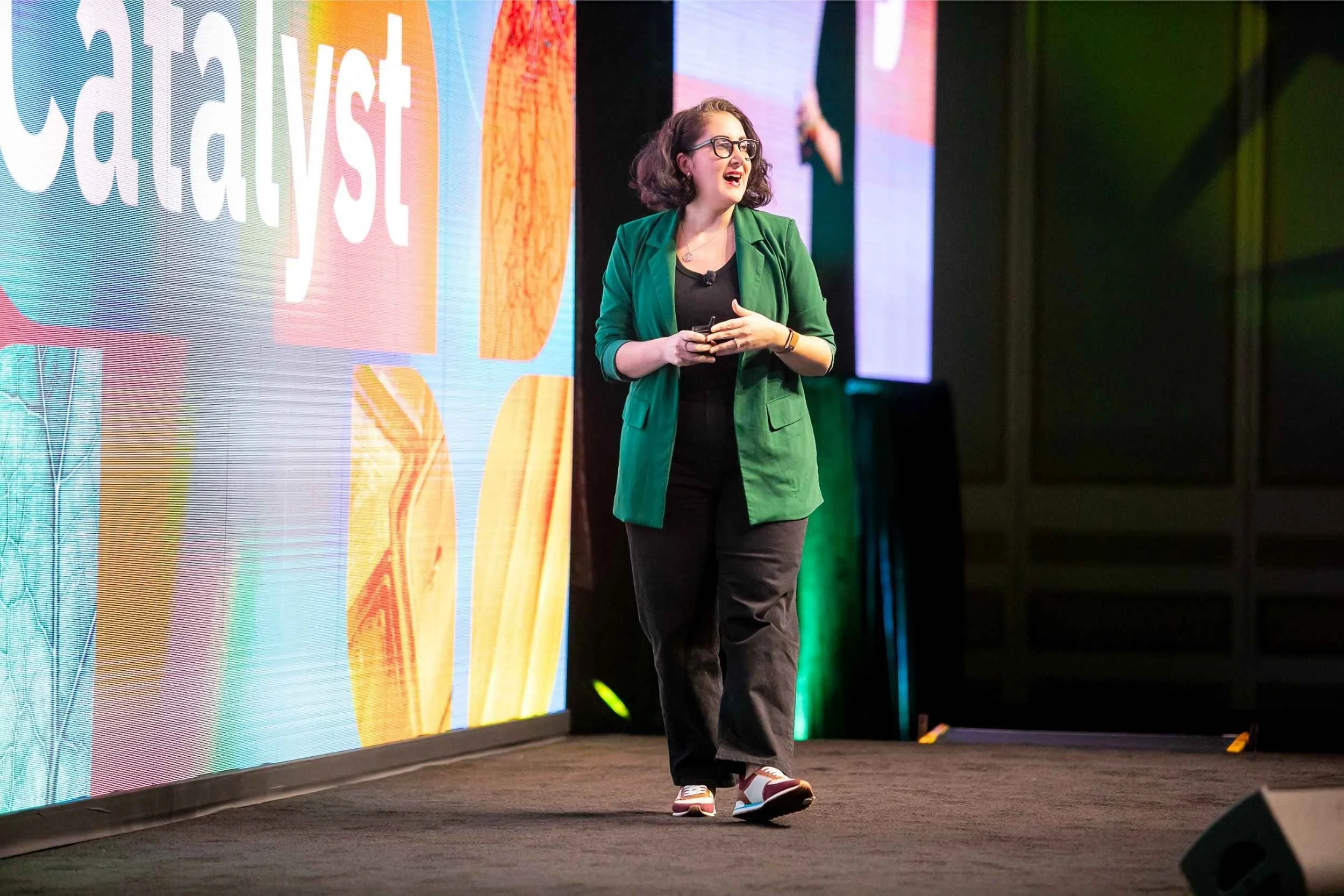 Speaker in a green jacket walks across the stage during a presentation at a Central Florida conference
