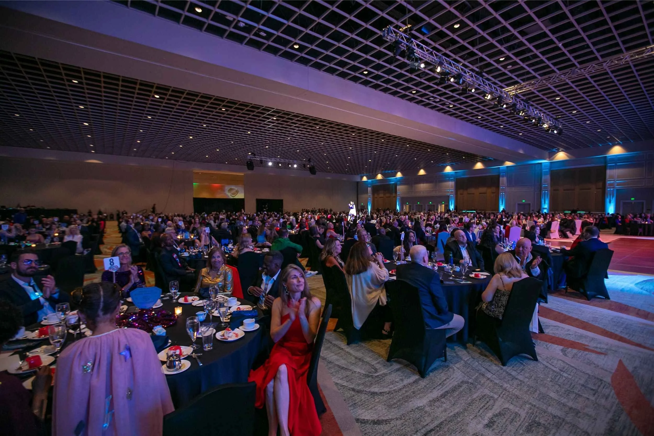 Audience seated at round tables watching the program at Rosen Shingle Creek