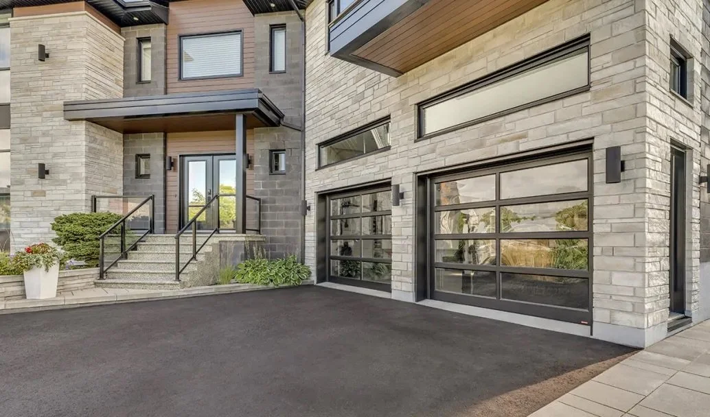 Modern house with a concrete stairway, glass garage doors, and a potted plant outside