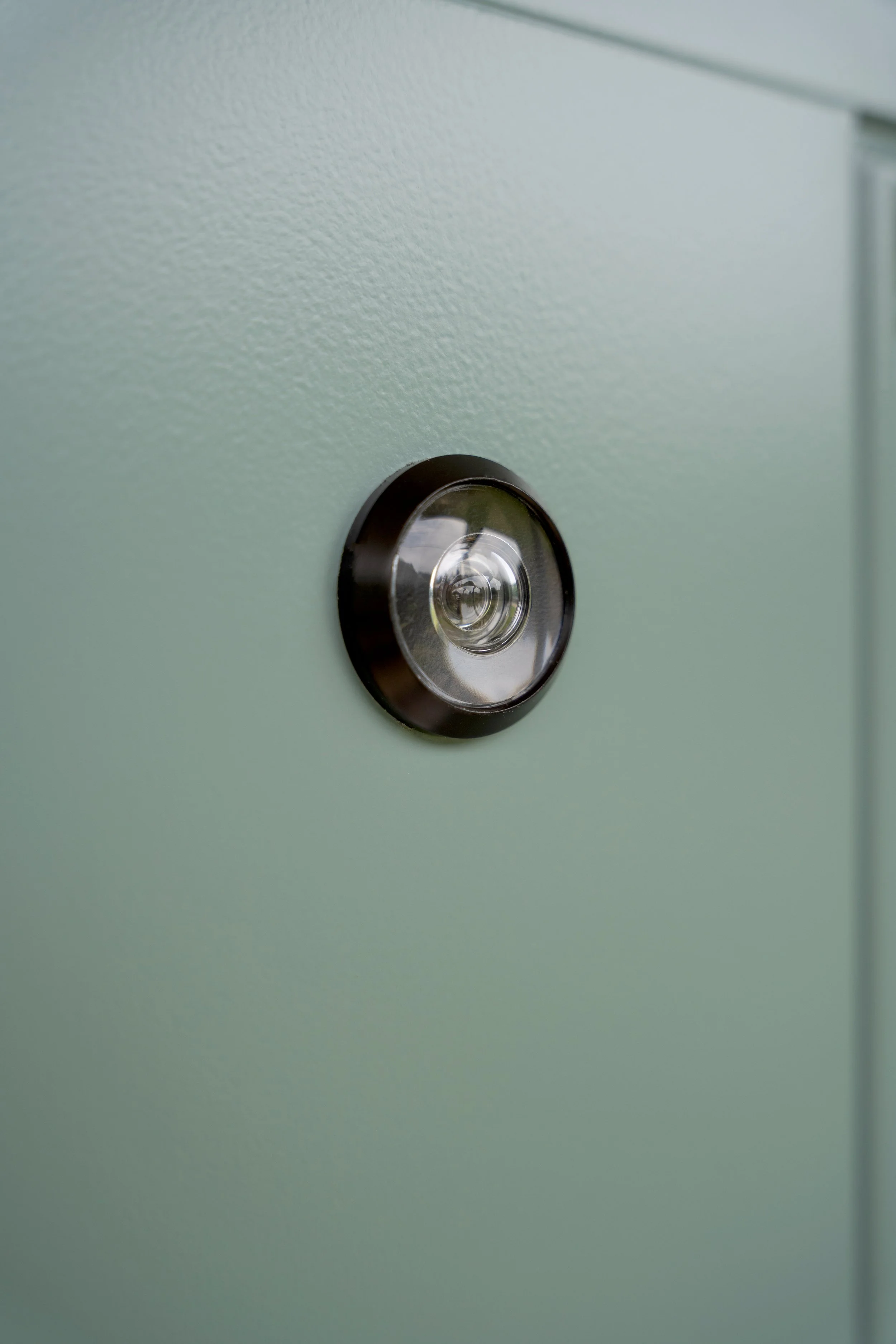 Close-up of a convex security mirror on a light green surface.