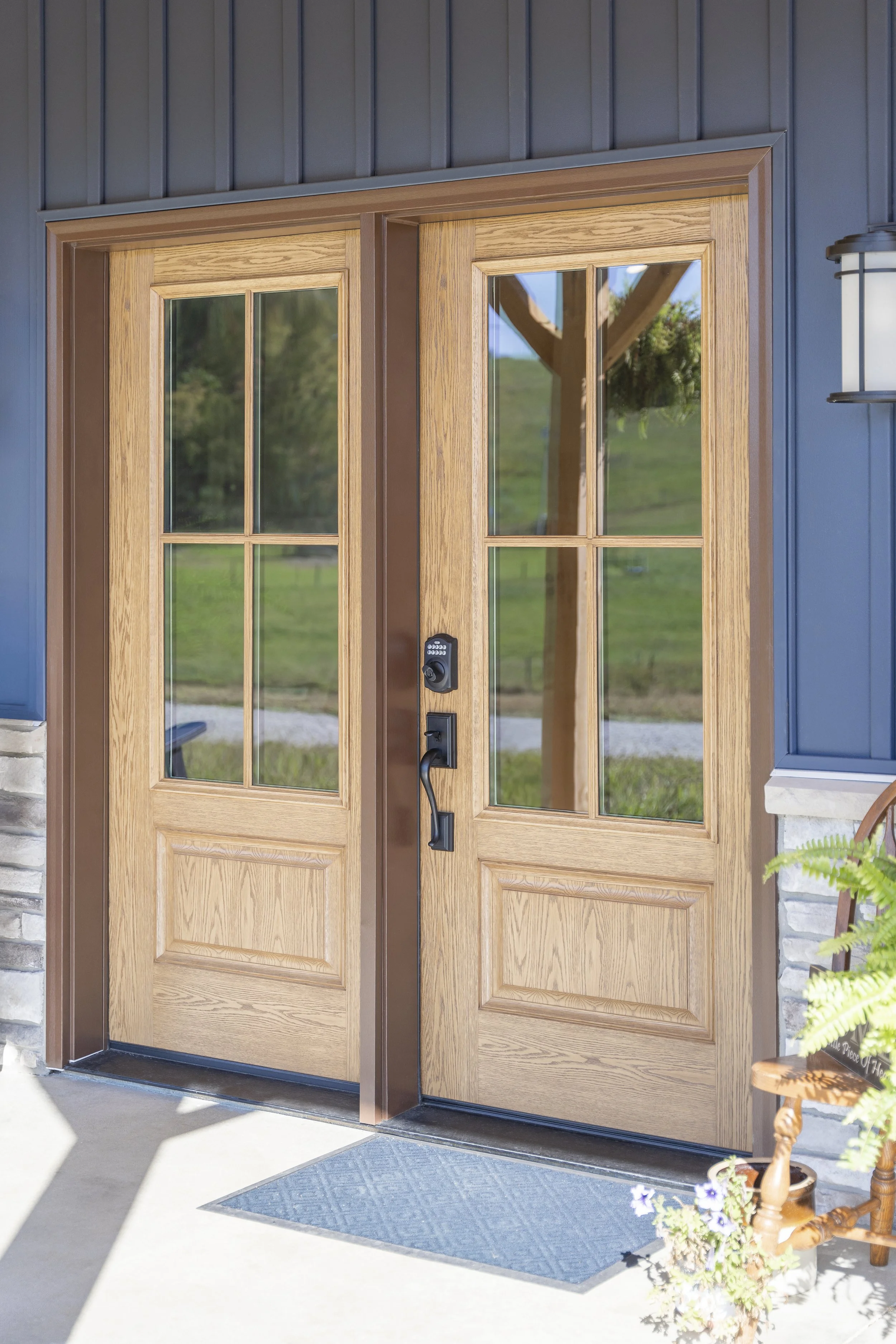 Double wooden front doors with glass panes and keypad lock at modern house entrance