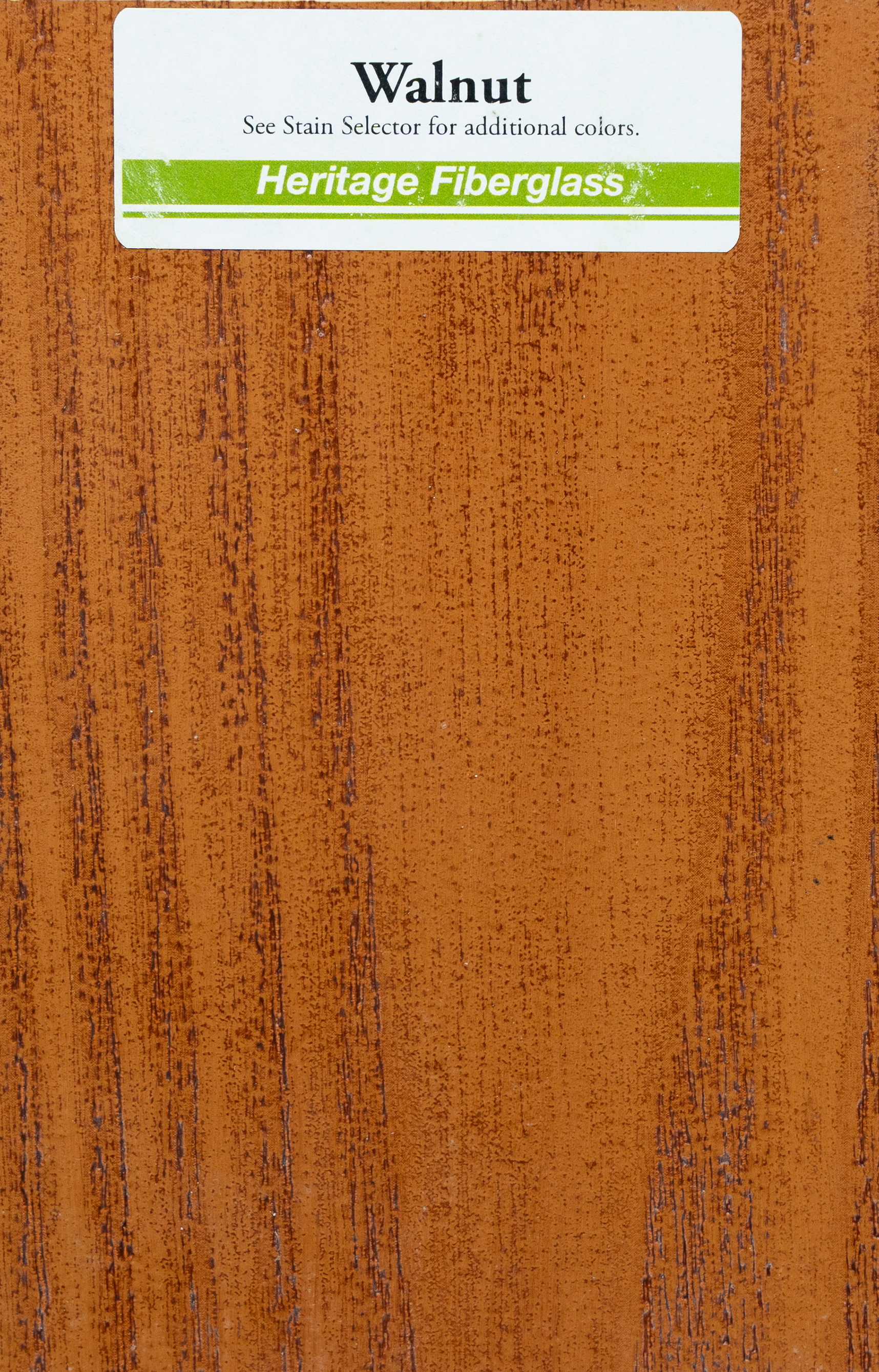 Close-up of a wood grain or veneer sample labeled 'Walnut' with a sticker indicating it is Heritage Fiberglass, used for furniture or cabinetry.