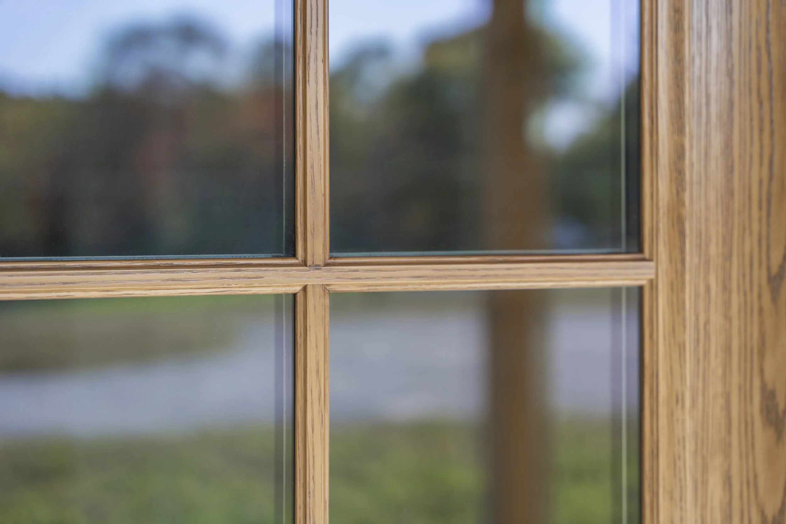 Close-up view of a wooden window frame with glass panes, showing a blurred outdoor background.