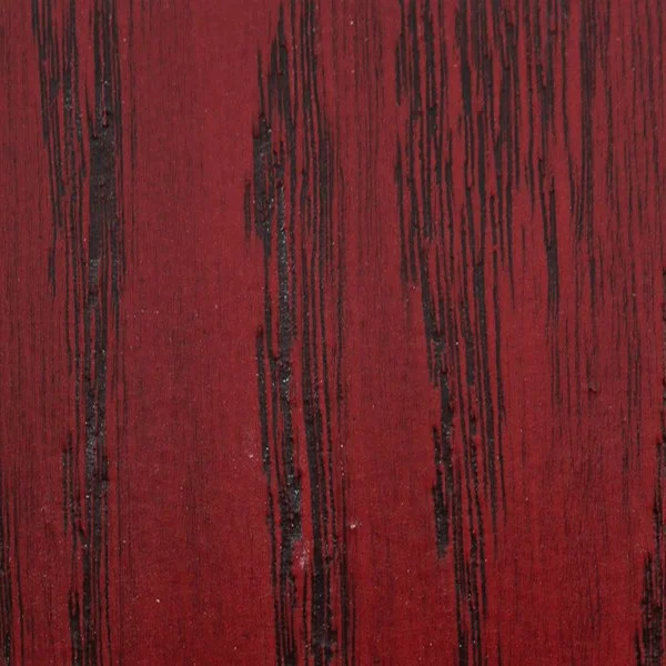 Close-up of red wooden surface with black streaks and grain pattern.