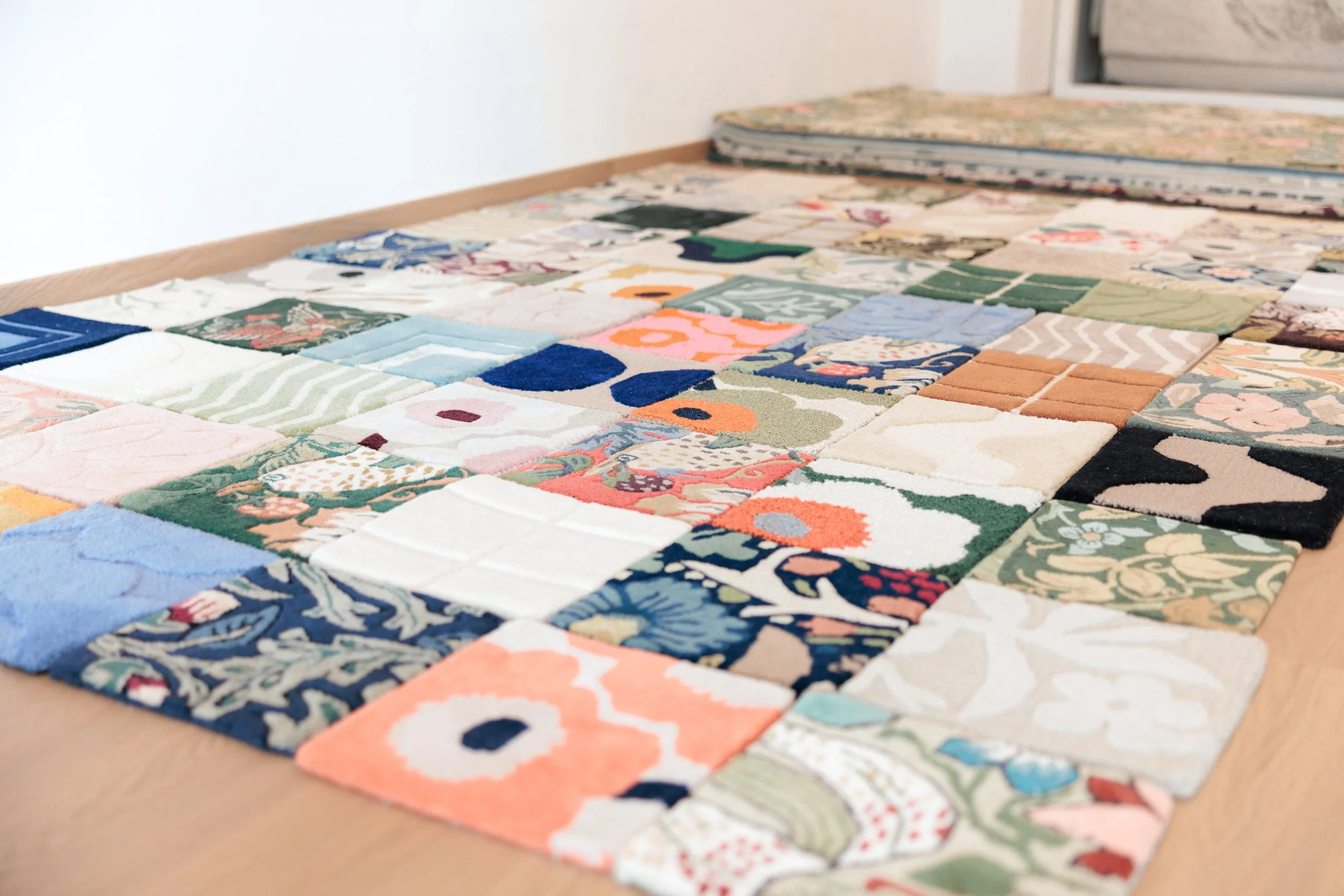 A close-up of a large assortment of colorful, patterned patches arranged on the floor. Loom & Stone Store Opening. Event Photography. Event Videography. Rugs. Carpets. Marimekko rugs.