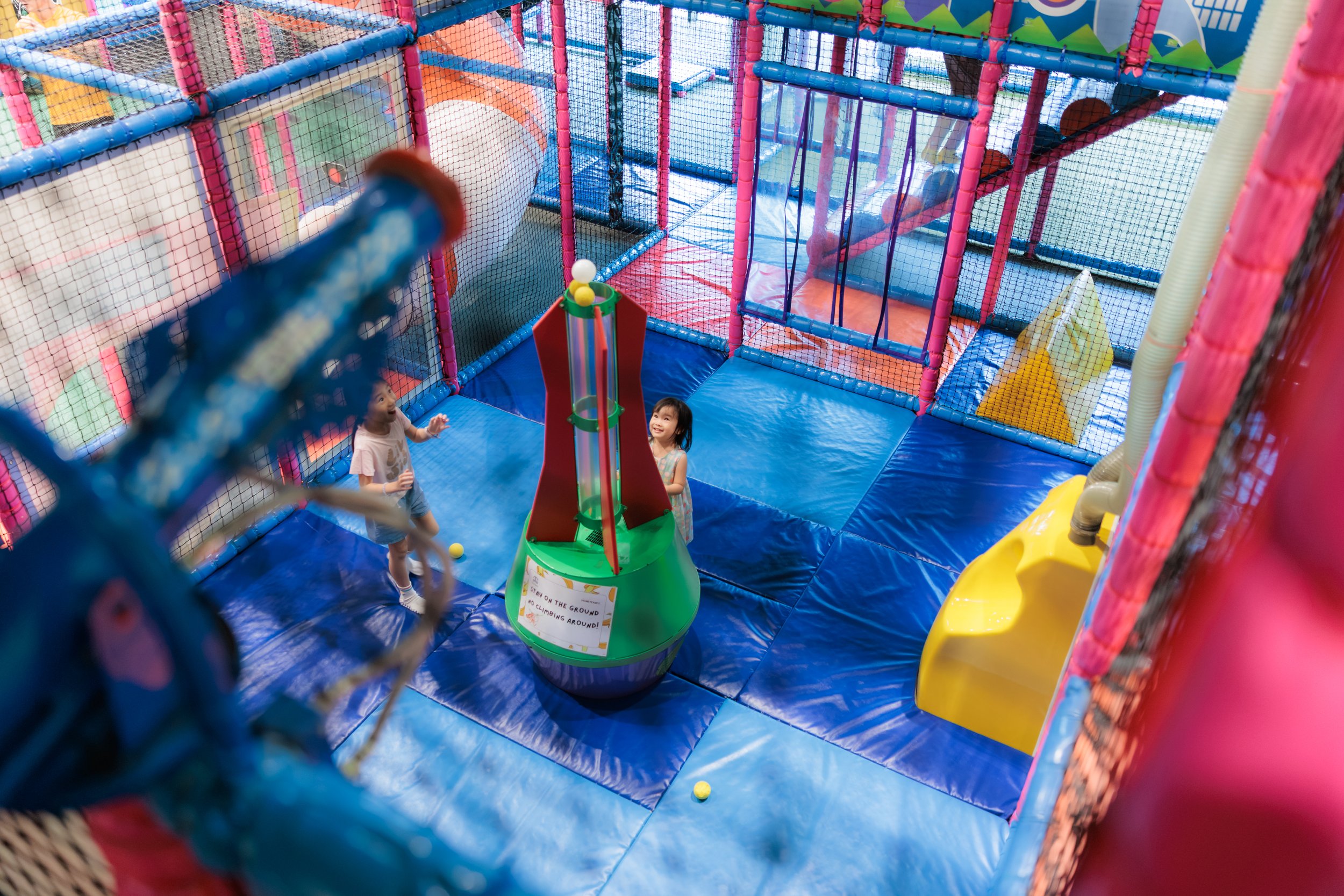 Children enjoying playing in an indoor playground structure with colorful netting, slides, and climbing areas. Family Photography Session. Birthday Photography Session. Event Photography. Khatib Adventure Birthday Party.