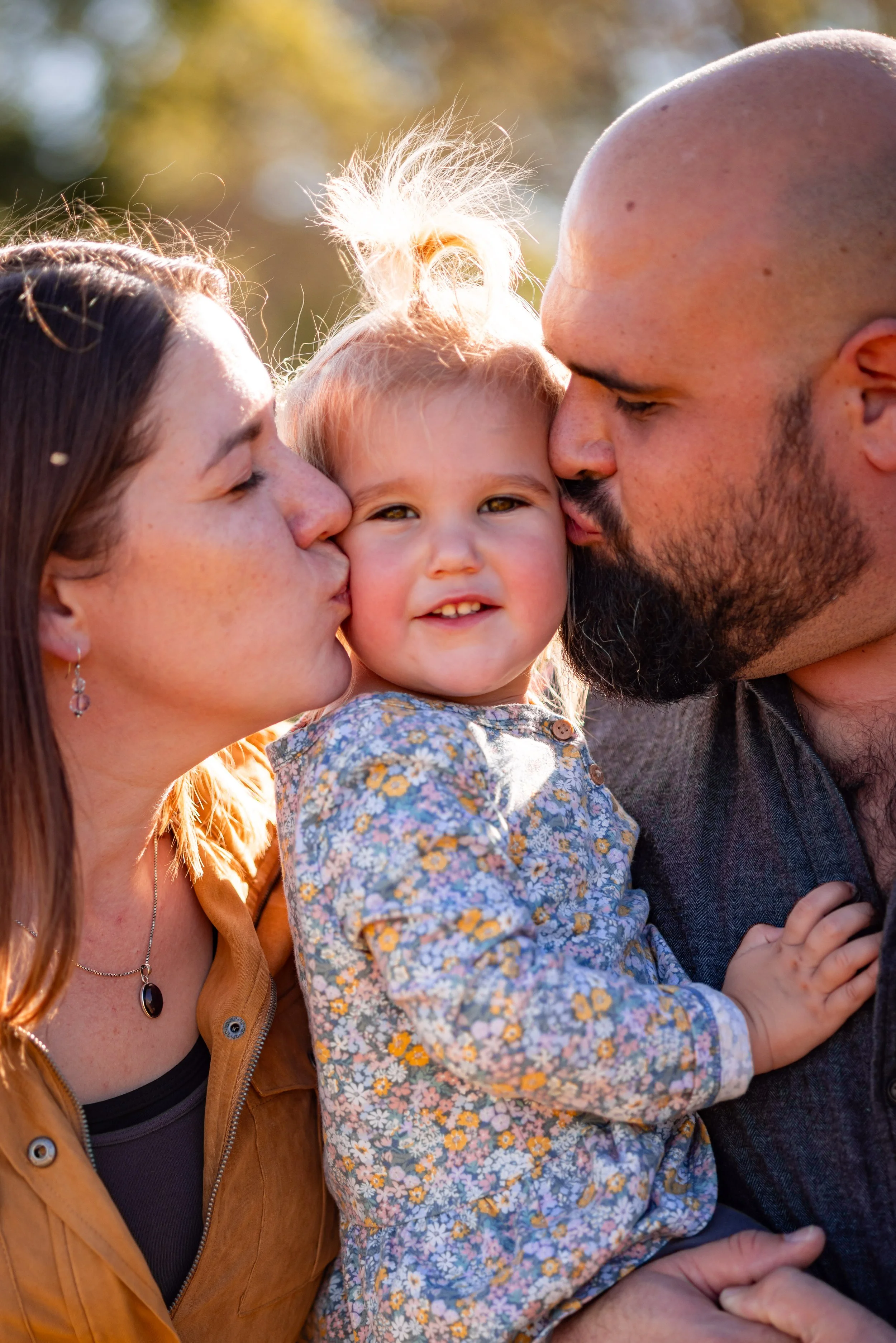 Sweet little toddler cuddling up with mom and dad during family session at Fresh Acres Farms in Monticello, MN