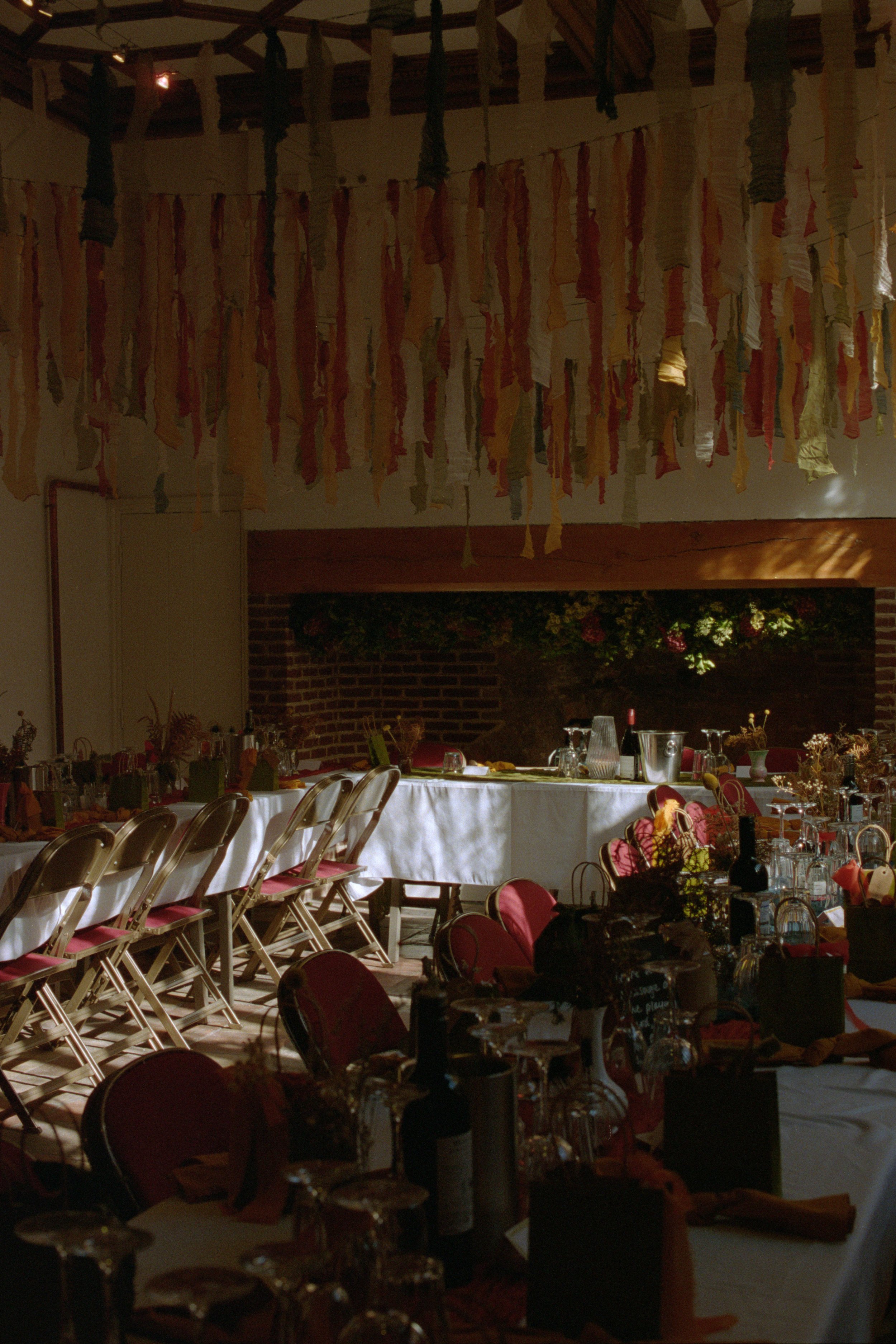 A dimly lit banquet hall with decorated tables and hanging fabric strips from the ceiling.