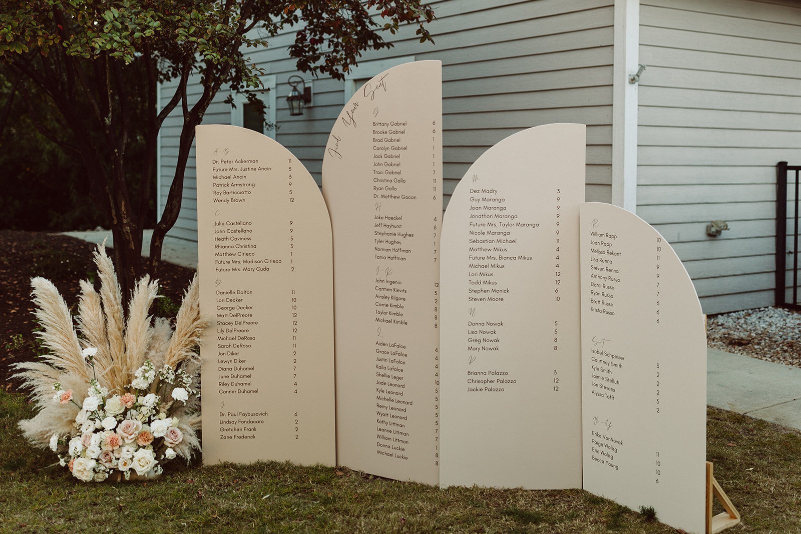  A wedding seating chart in front of a house in the Outer Banks with pampas grass. 