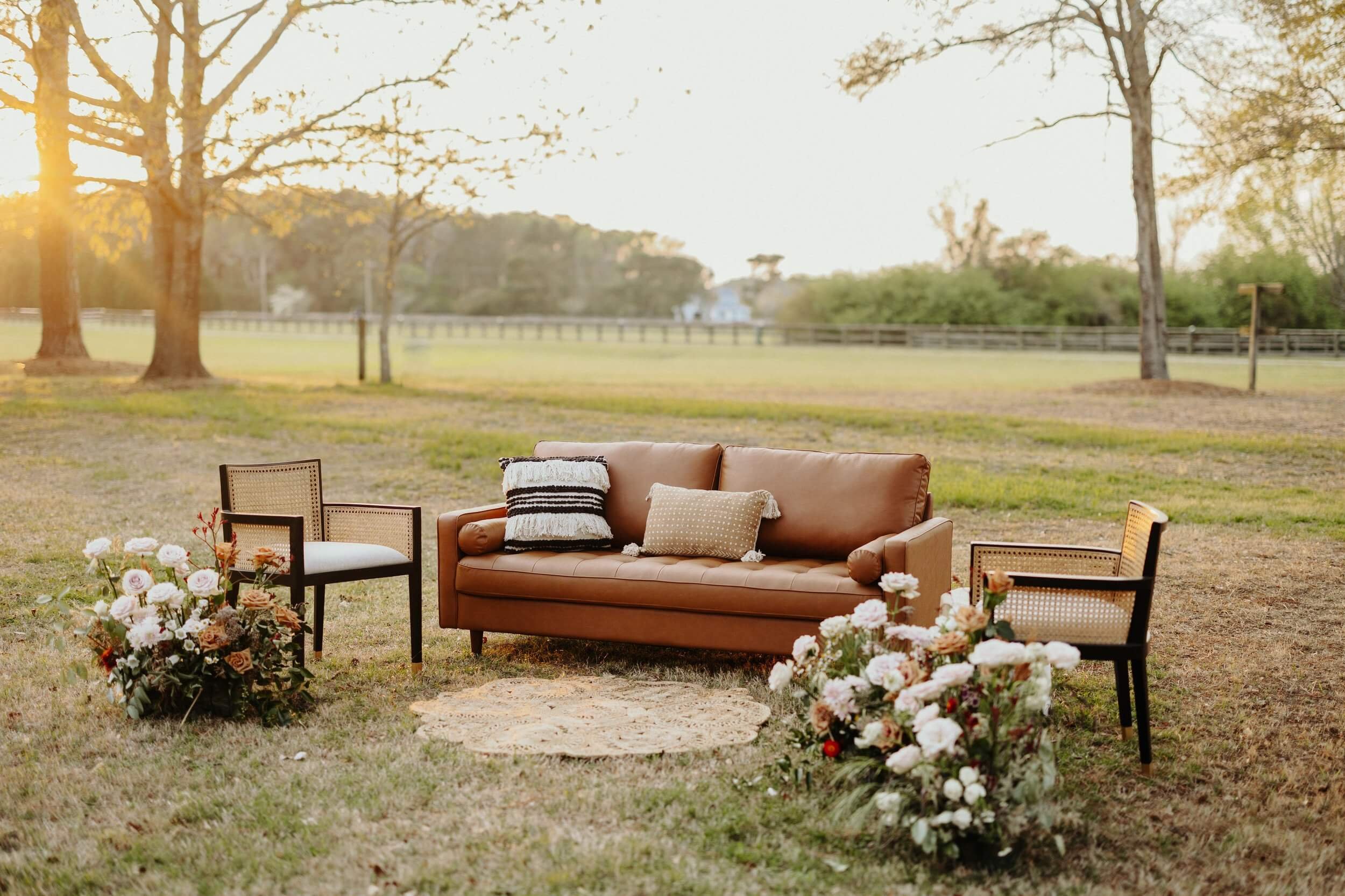  A leather sofa rental and chairs at event venue with flowers 