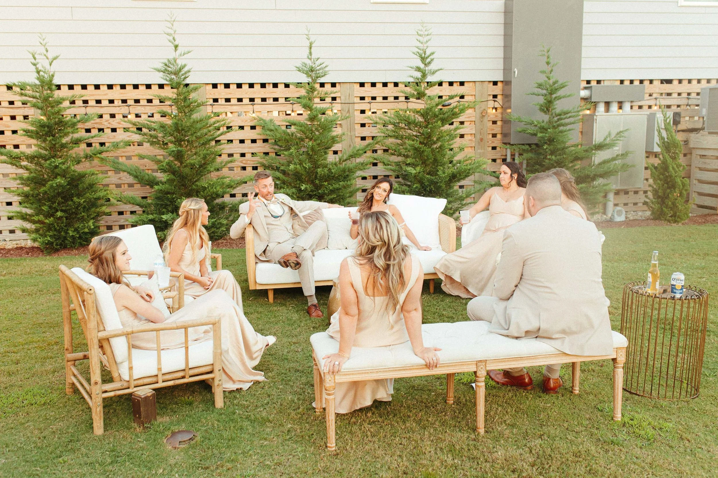 A group of people sitting on lounge collection furniture rentals in backyard