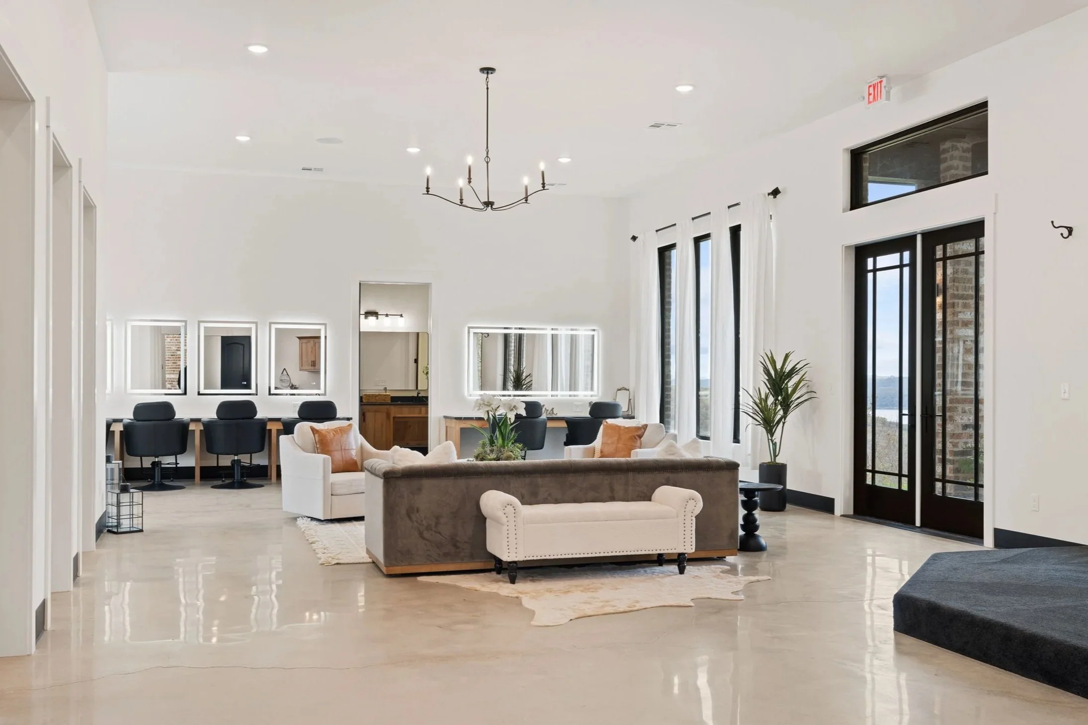 Interior of a modern, spacious lounge with seating areas, mirrors, and large windows.