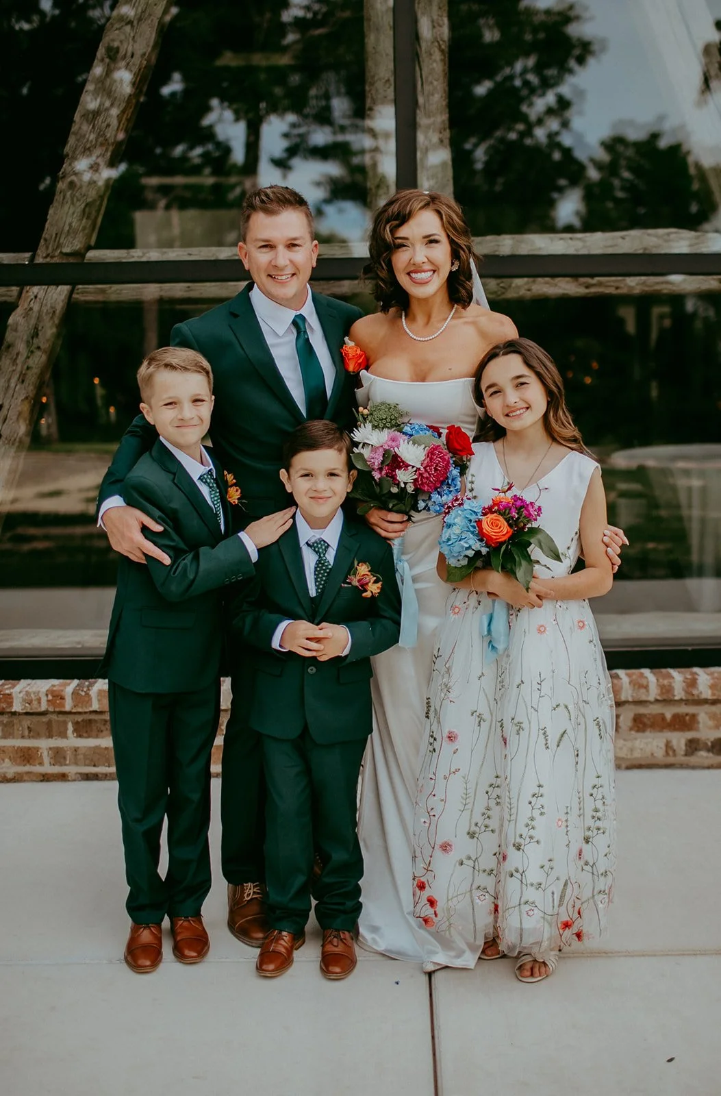 Bride and groom standing in front of a glass window with their family. 