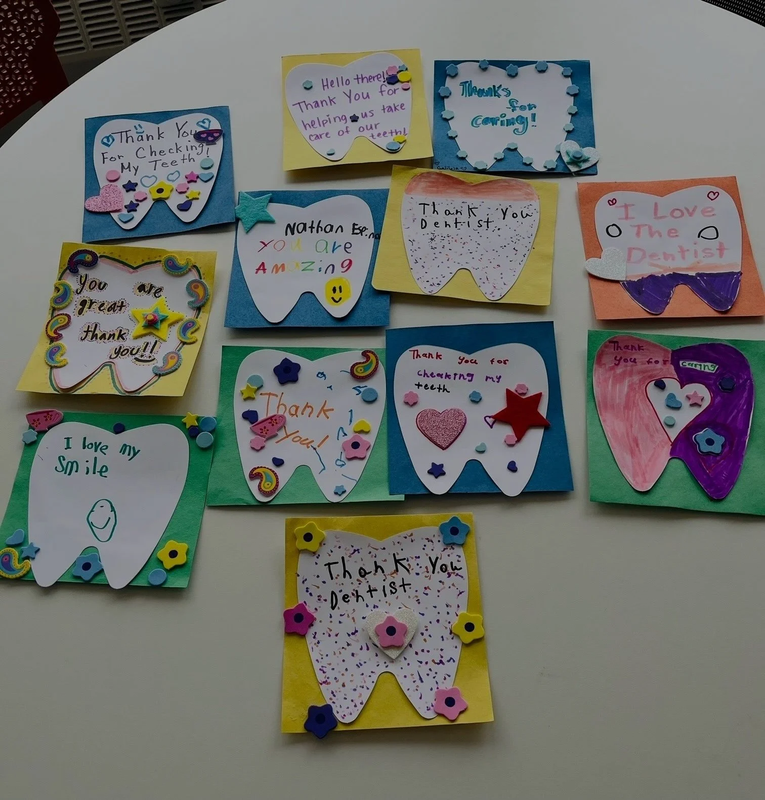 Colorful handmade thank you cards for dentists, decorated with foam stickers, drawings, and handwritten messages expressing gratitude for dental care.