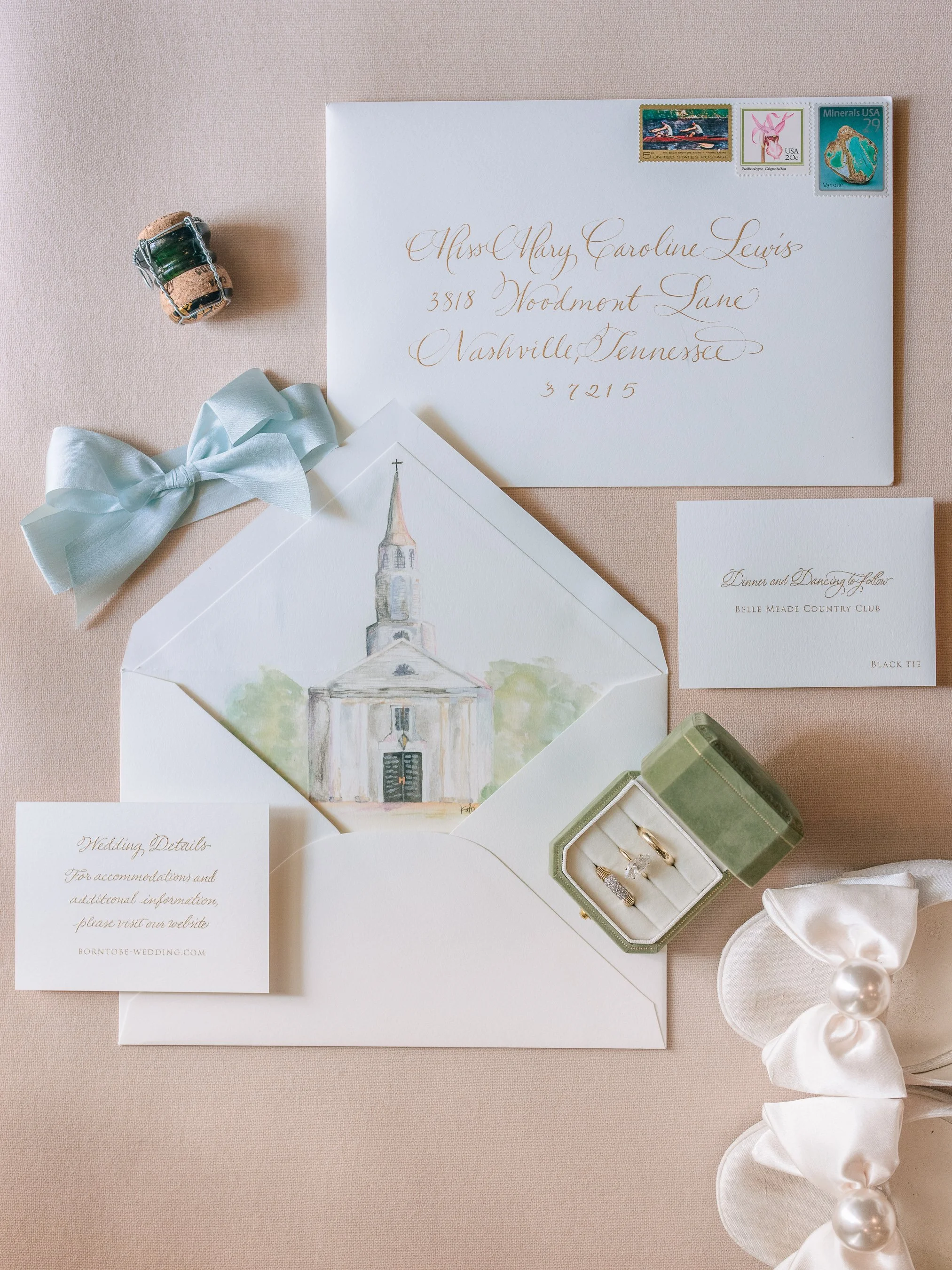 Wedding invitation, envelope with calligraphy, watercolor church illustration, jewelry box with rings, RSVP card, decorative silk bow, pearl and ribbon boutonniere, postage stamps.