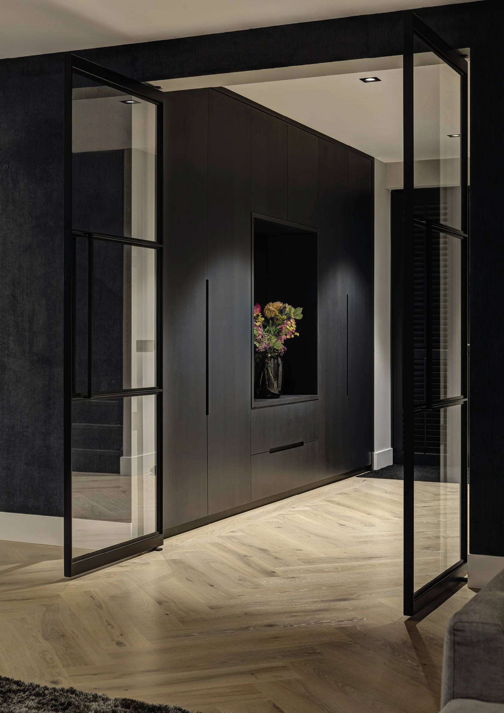 Interieur van een modern huis met zwarte muurkast en glazen dubbele deuren.