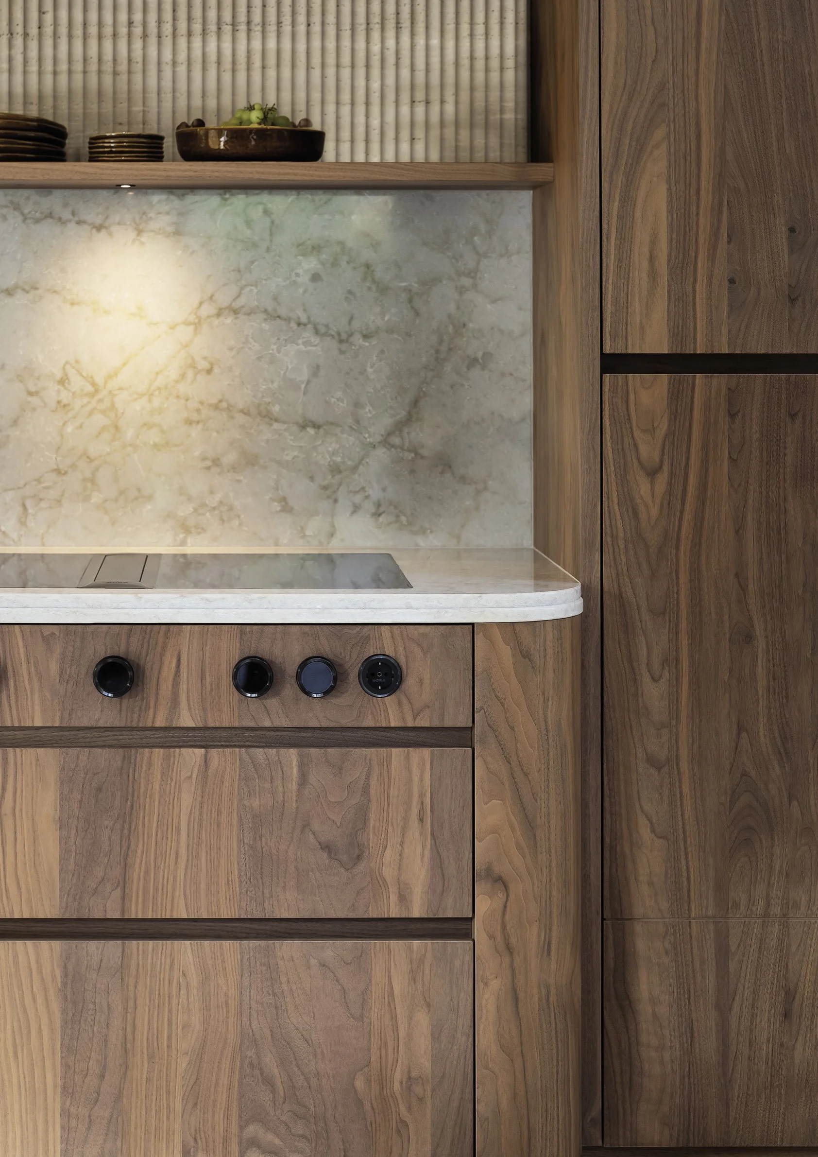 Houten keuken met marmeren achterwand en een elektrische kookplaat.