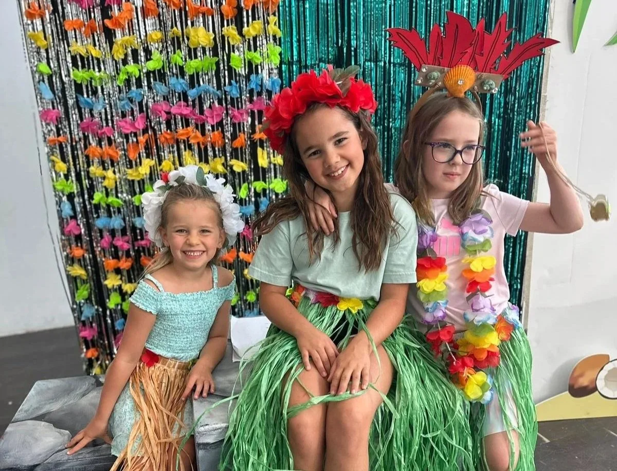 Sparks summer camp students holding tropical props and performing on stage during Friday showcase.